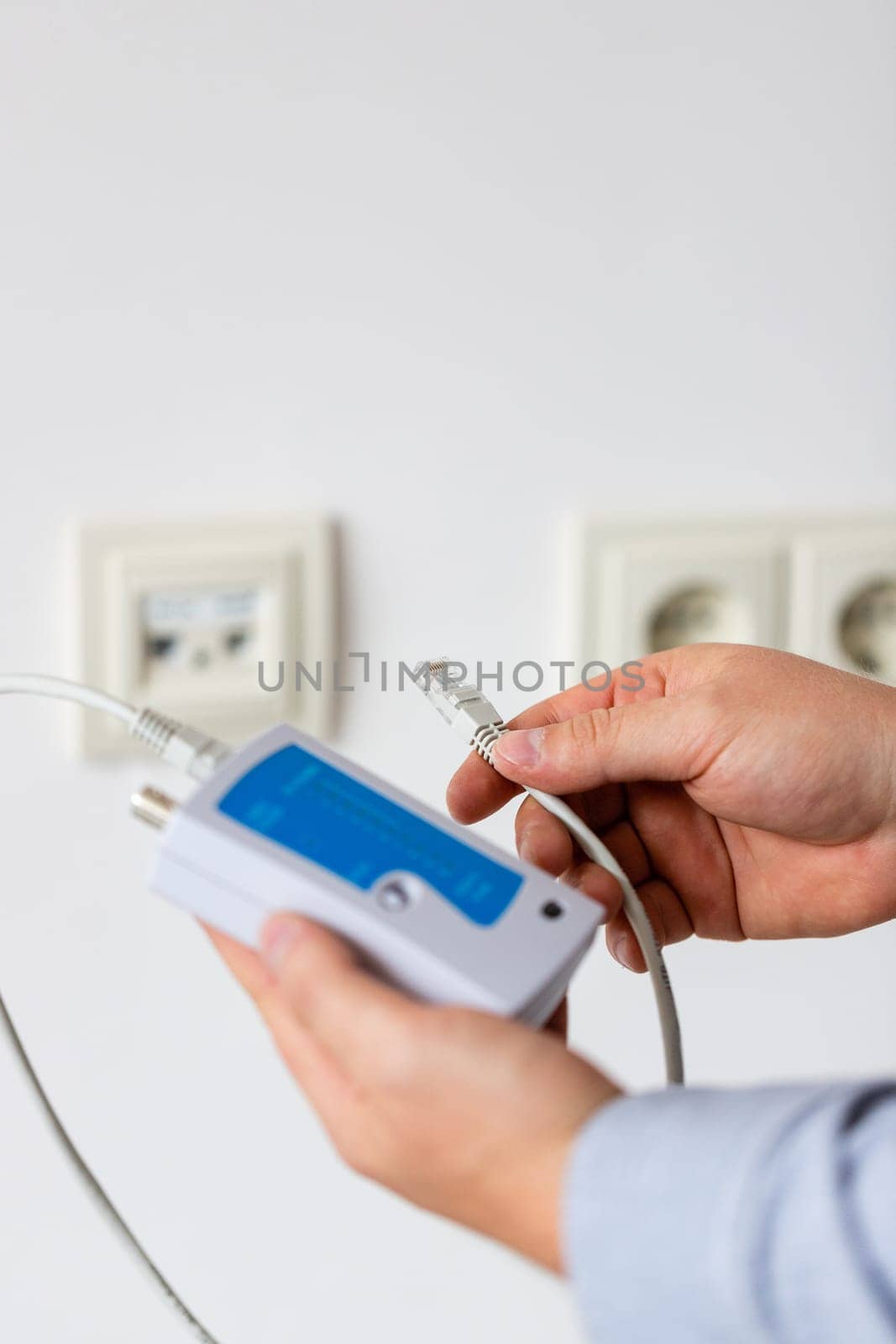Network cable tester. Testing structured cabling using qualified cable performance tester. Close up of network cable tester with UTP cable in hands of male worker.