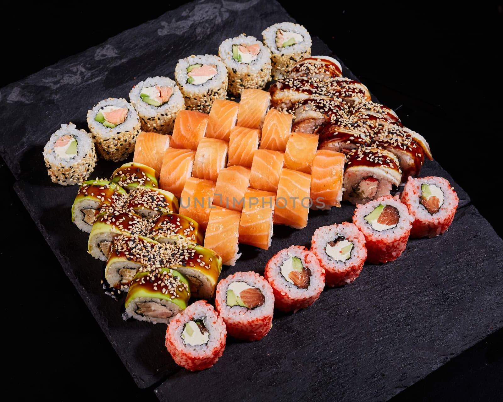 Japanese sushi set. Different types of rolls on a stone board for sushi on a black background. Food background.