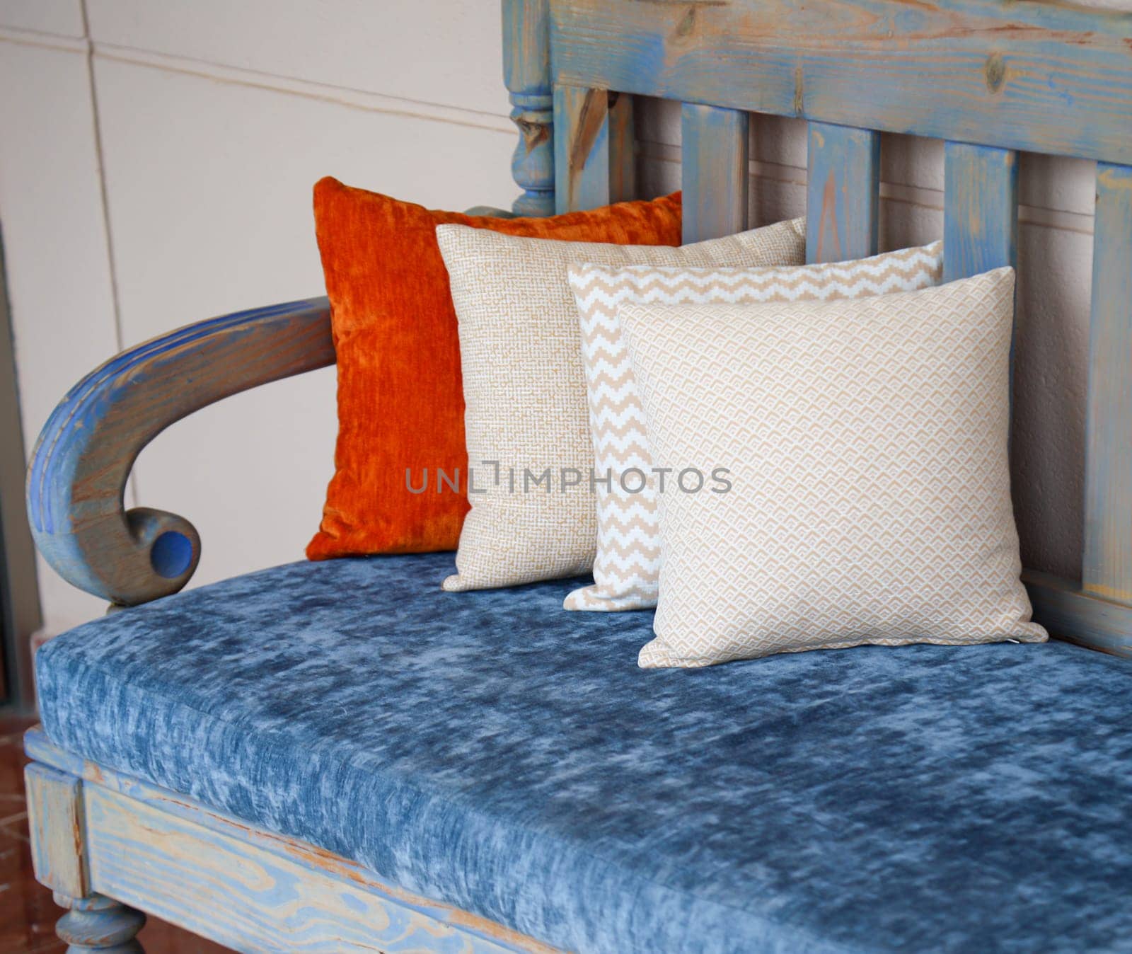 Four colored cushions stand on a wooden bench.