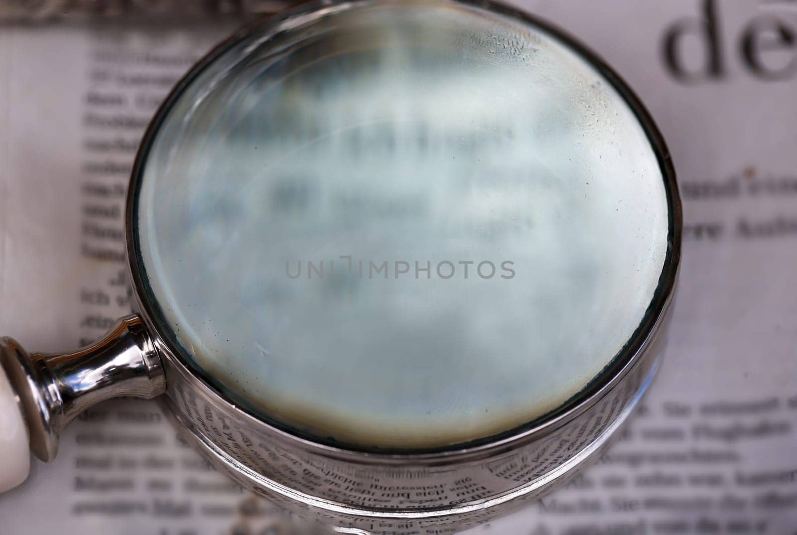 A magnifying glass, a reading aid lies on an old newspaper.