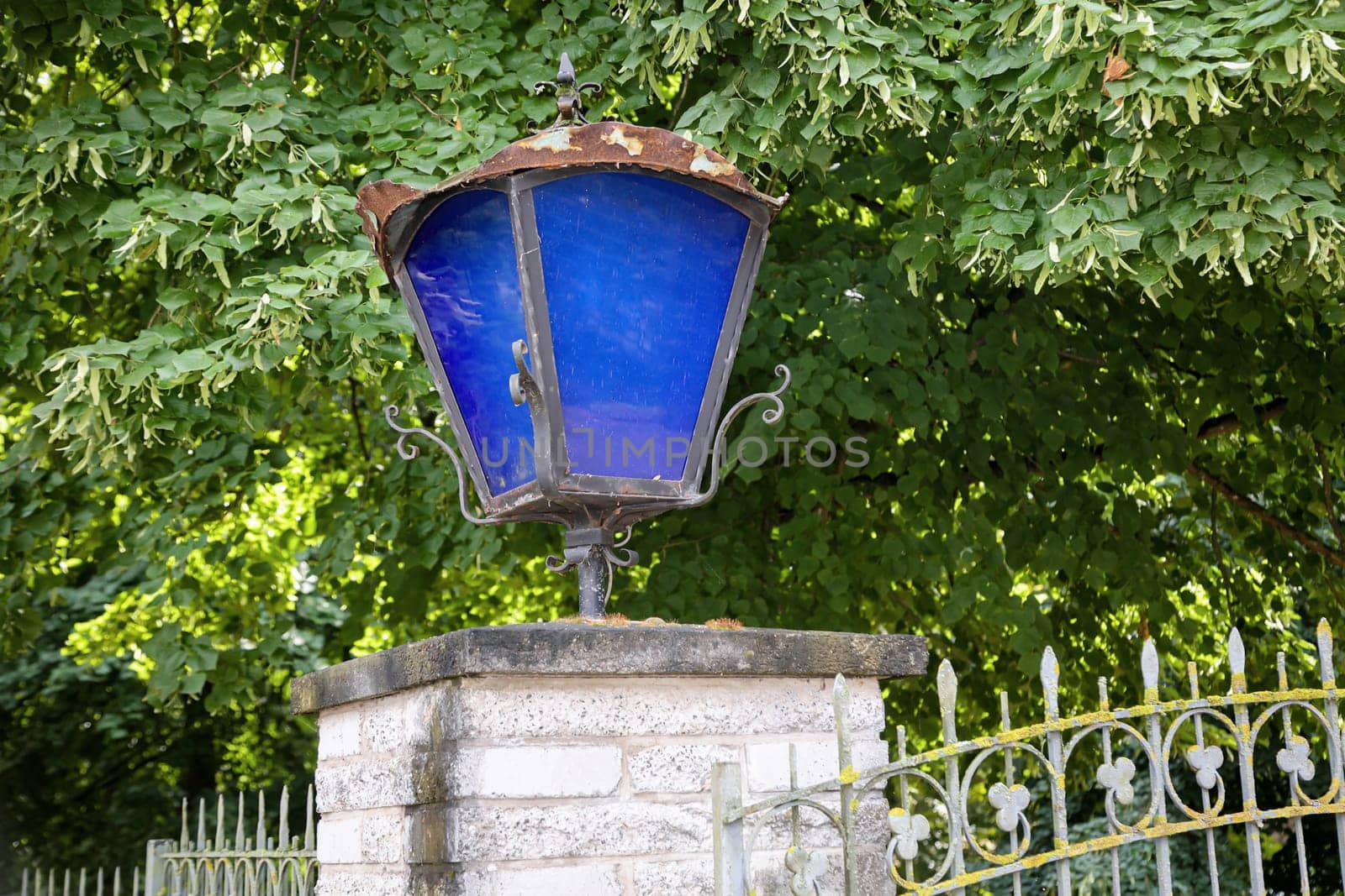 A lantern with blue discson a gatepost.