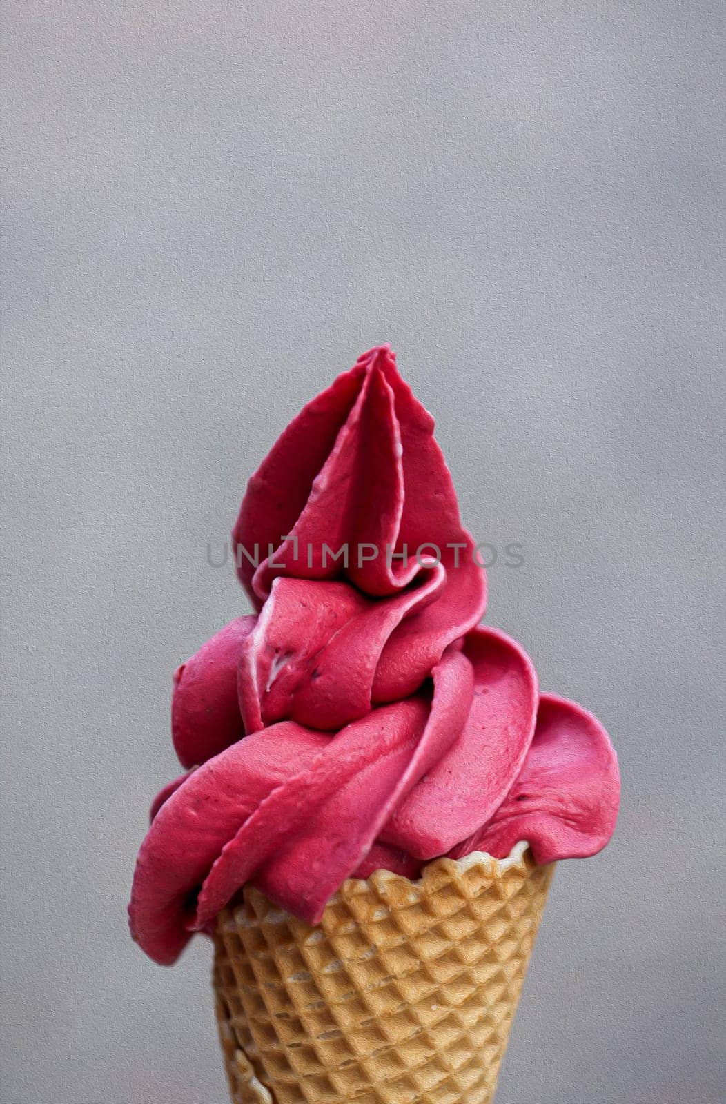 A waffle ice cream cone filled with a delicious freshly made raspberry soft serve ice cream.
