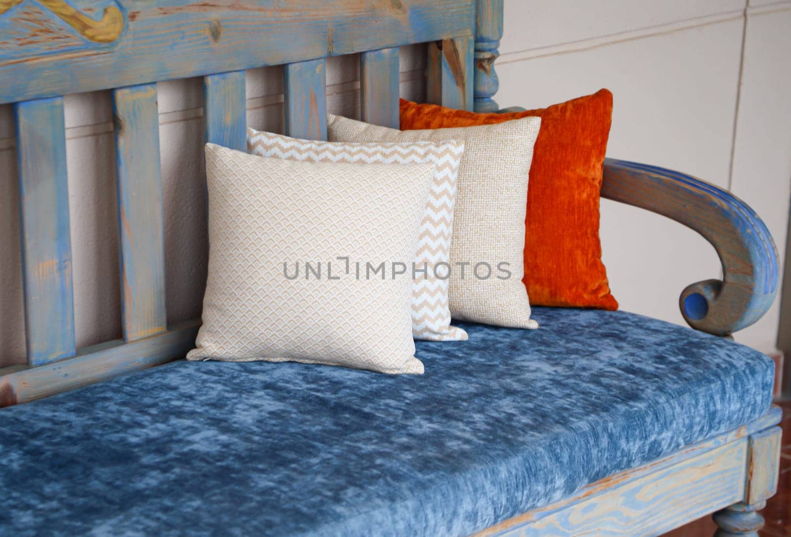 Four colored cushions stand on a wooden bench.