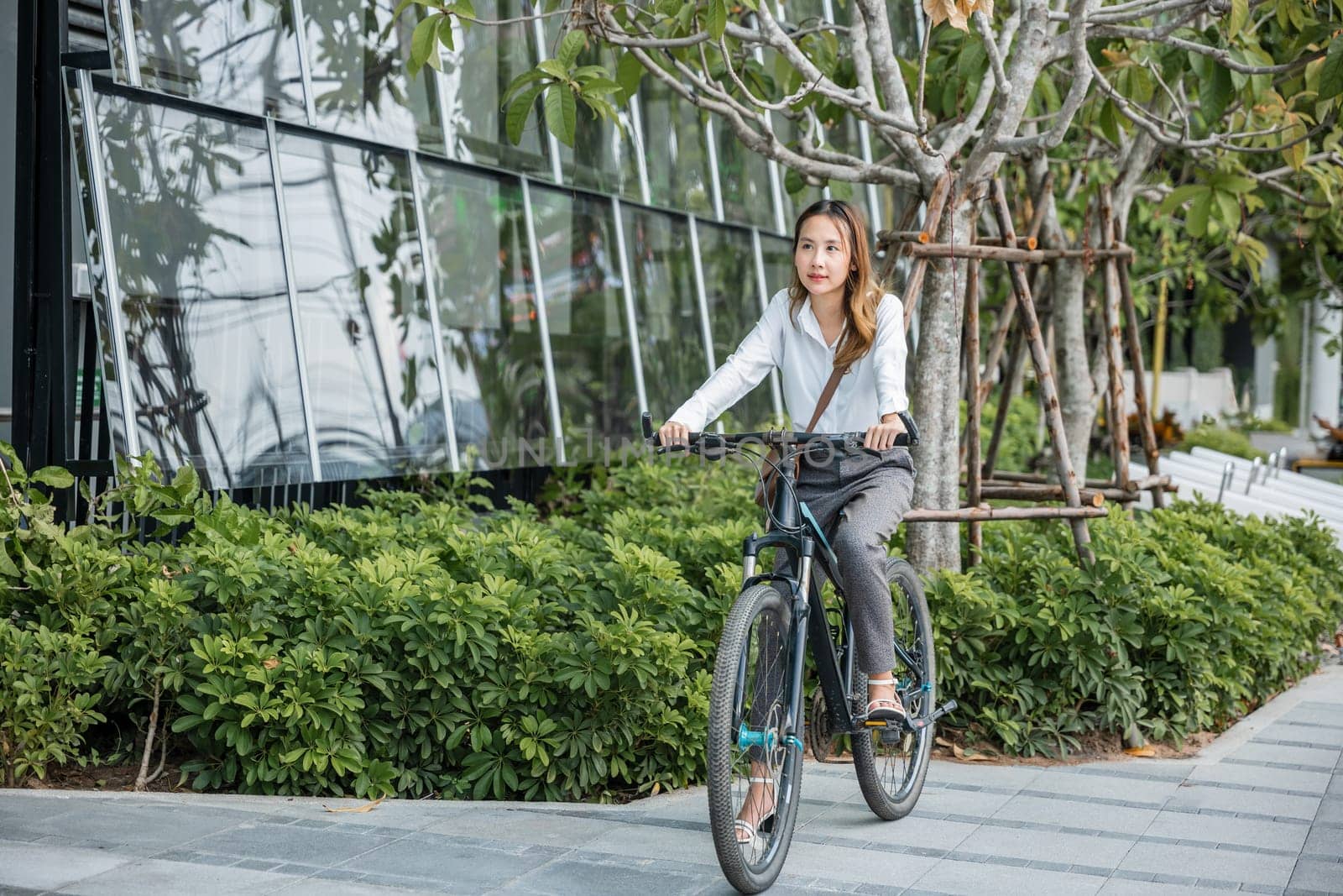 Asian beautiful young businesswoman with helmet riding bicycle go to office work at city street with bicycle in morning, Happy lifestyle woman bike after business work outside building , Eco friendly