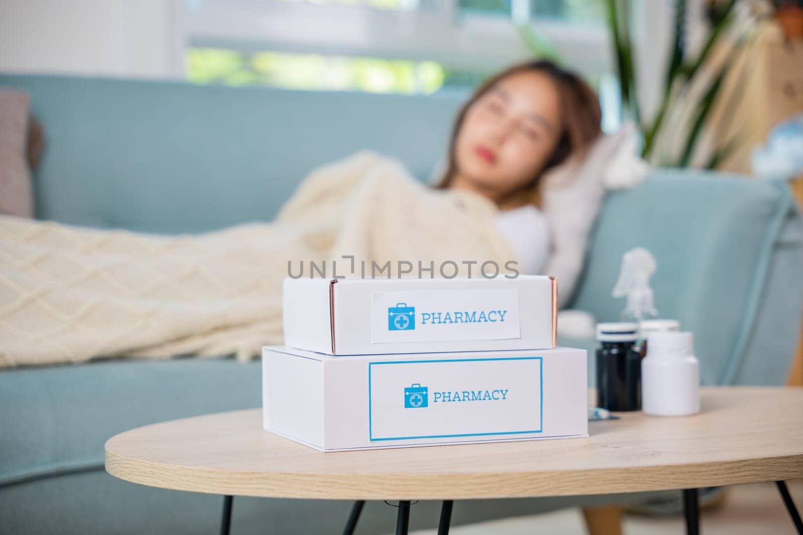 Asian beautiful female use pharmacy first aid kit box delivery service from hospital, Young woman tired sick she sleep and resting on sofa after take medicines pills in living room at home, healthcare