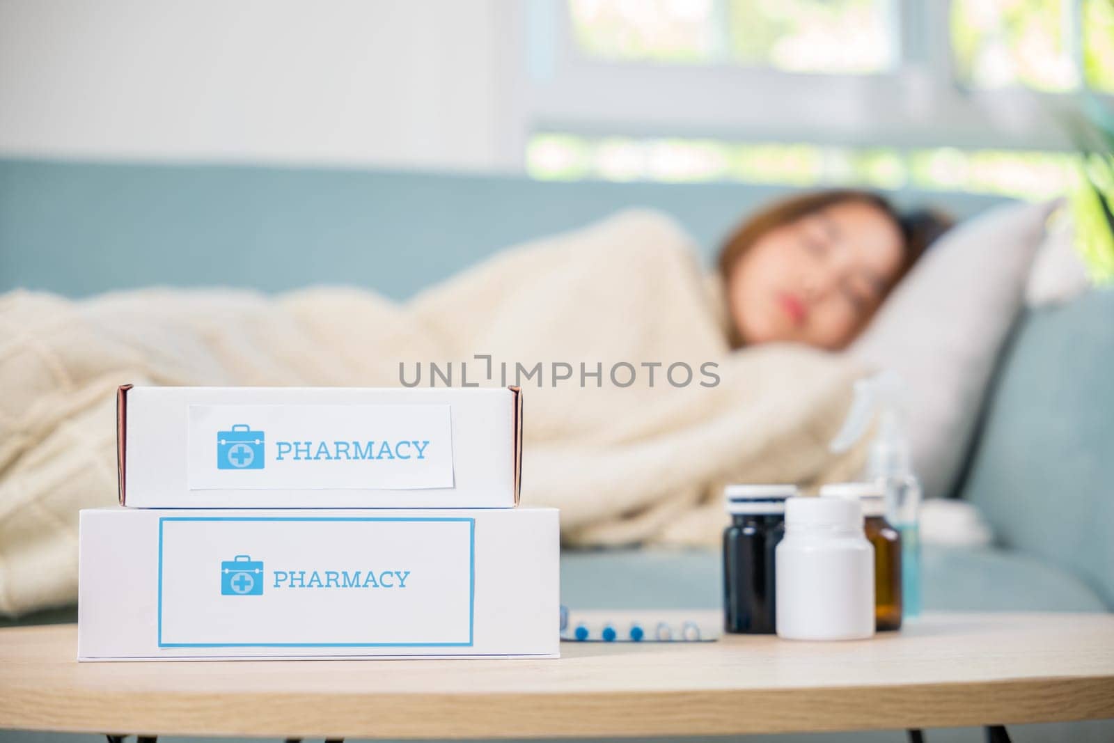 Asian beautiful female use pharmacy first aid kit box delivery service from hospital, Young woman tired sick she sleep and resting on sofa after take medicines pills in living room at home, healthcare