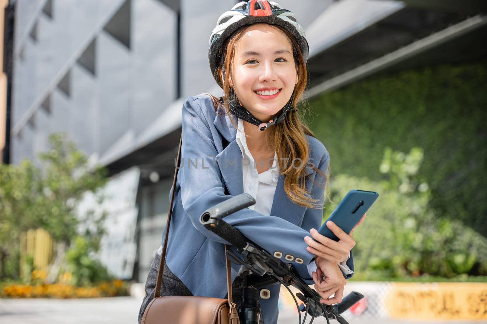 Asian smiling young woman with helmet hold mobile smart phone talk with business during go to office work at street with bicycle, Eco friendly, Lifestyle business female using bike outdoor in morning