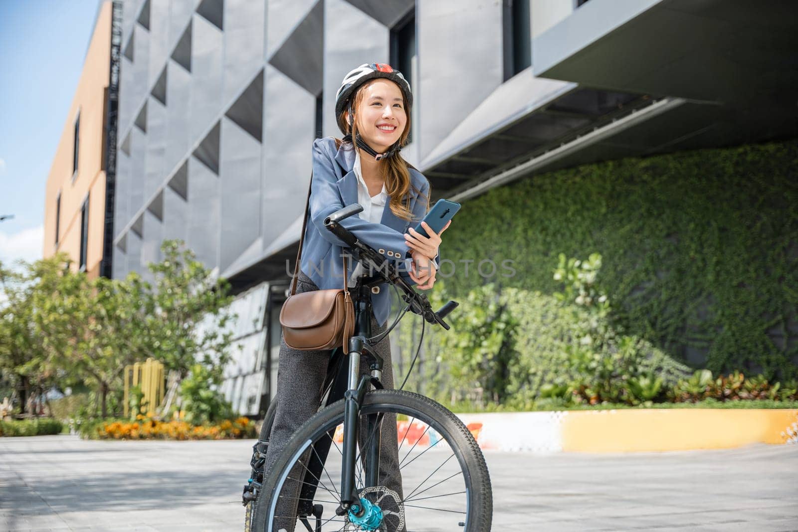 Asian smiling young woman with helmet hold mobile smart phone talk with business during go to office work at street with bicycle, Eco friendly, Lifestyle business female using bike outdoor in morning