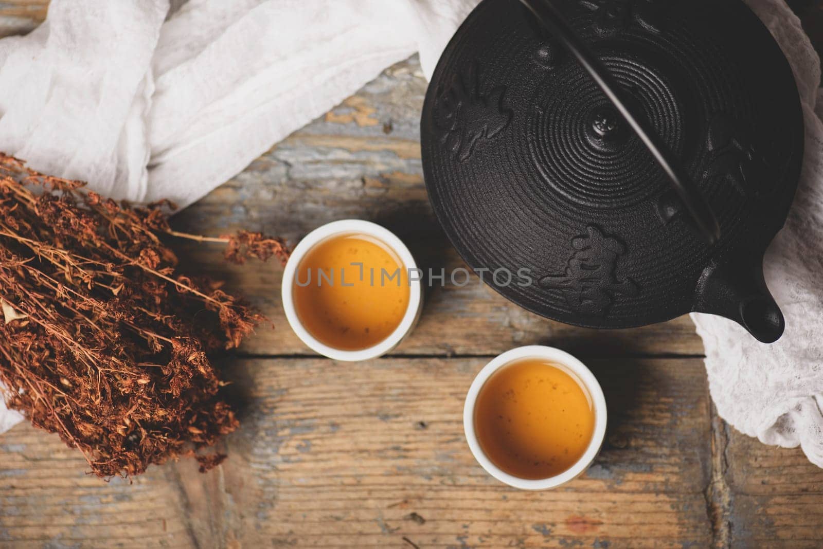 Traditional japanese herbal tea recipe prepared in cast iron teapot with organic dry herbs. Top view of asian traditional hot beverage on wooden table.