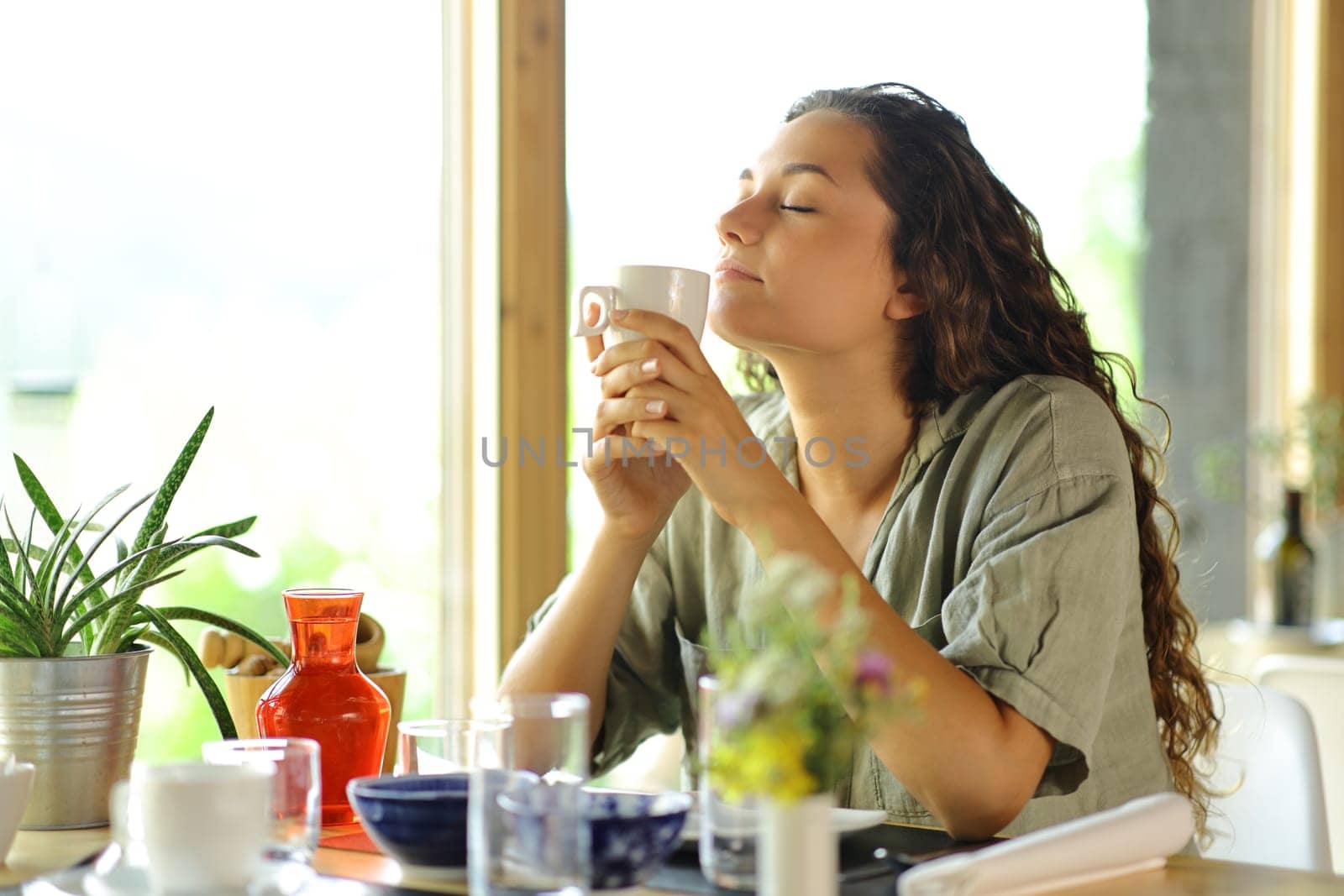 Woman smelling coffee aroma sitting in a restaurant