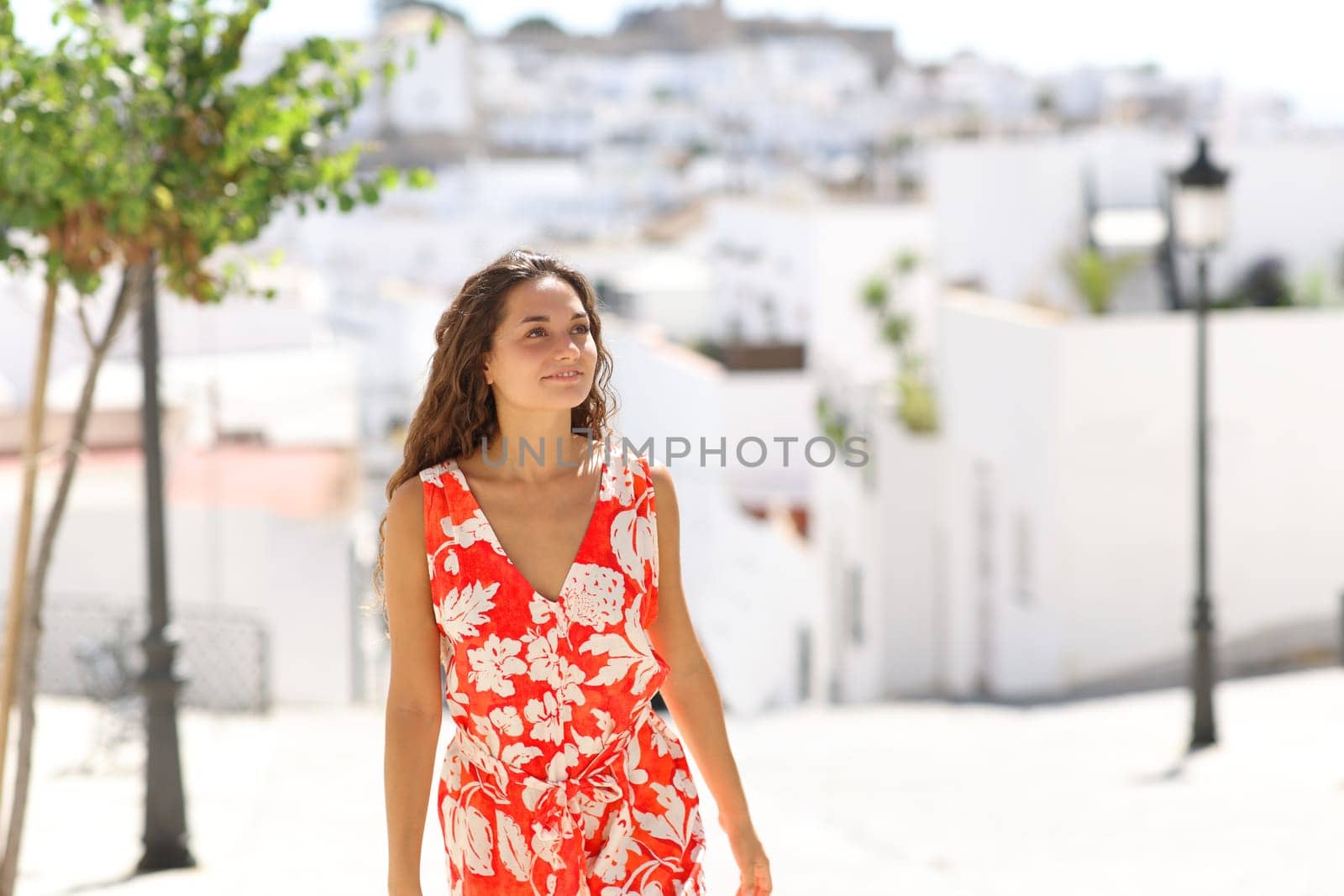Happy woman in red walking in a white town street on summer vacation