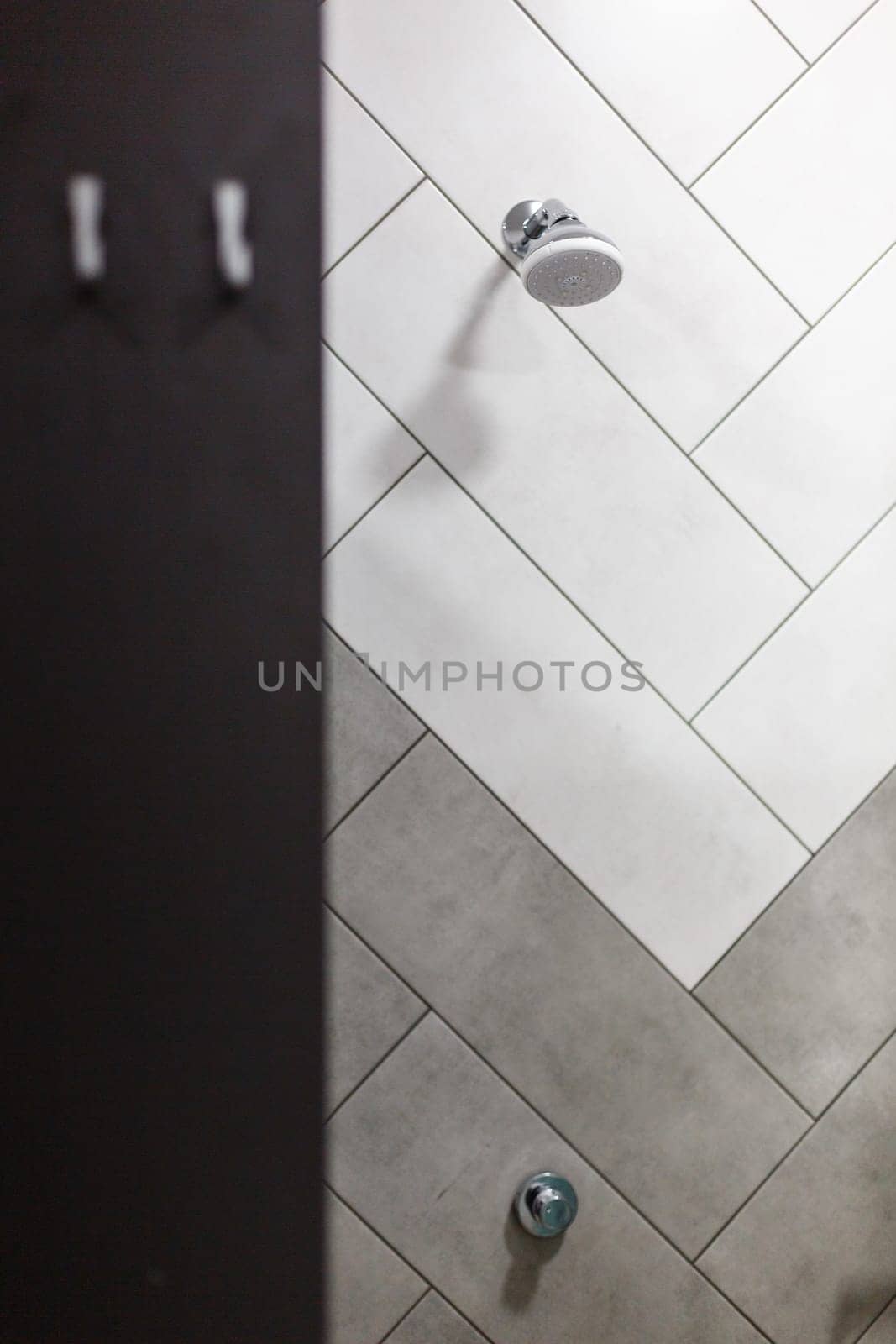 Shower equipment. Stylish minimalist shower head built into wall in modern bathroom. Shower funnel on the wall with white and gray tiles. Sale of plumbing concept.