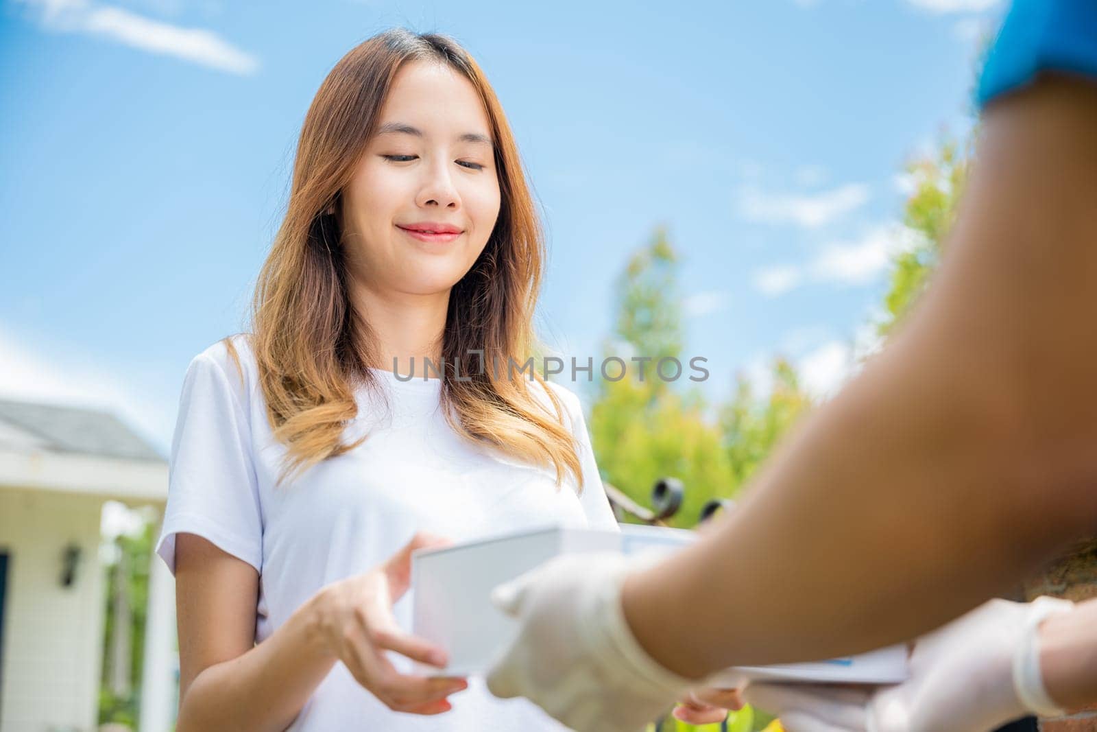 Sick Asian young woman receive medicine first aid pharmacy box from hospital delivery service, happy female receiving patient medicine drug from delivery man, healthcare medicine online concept