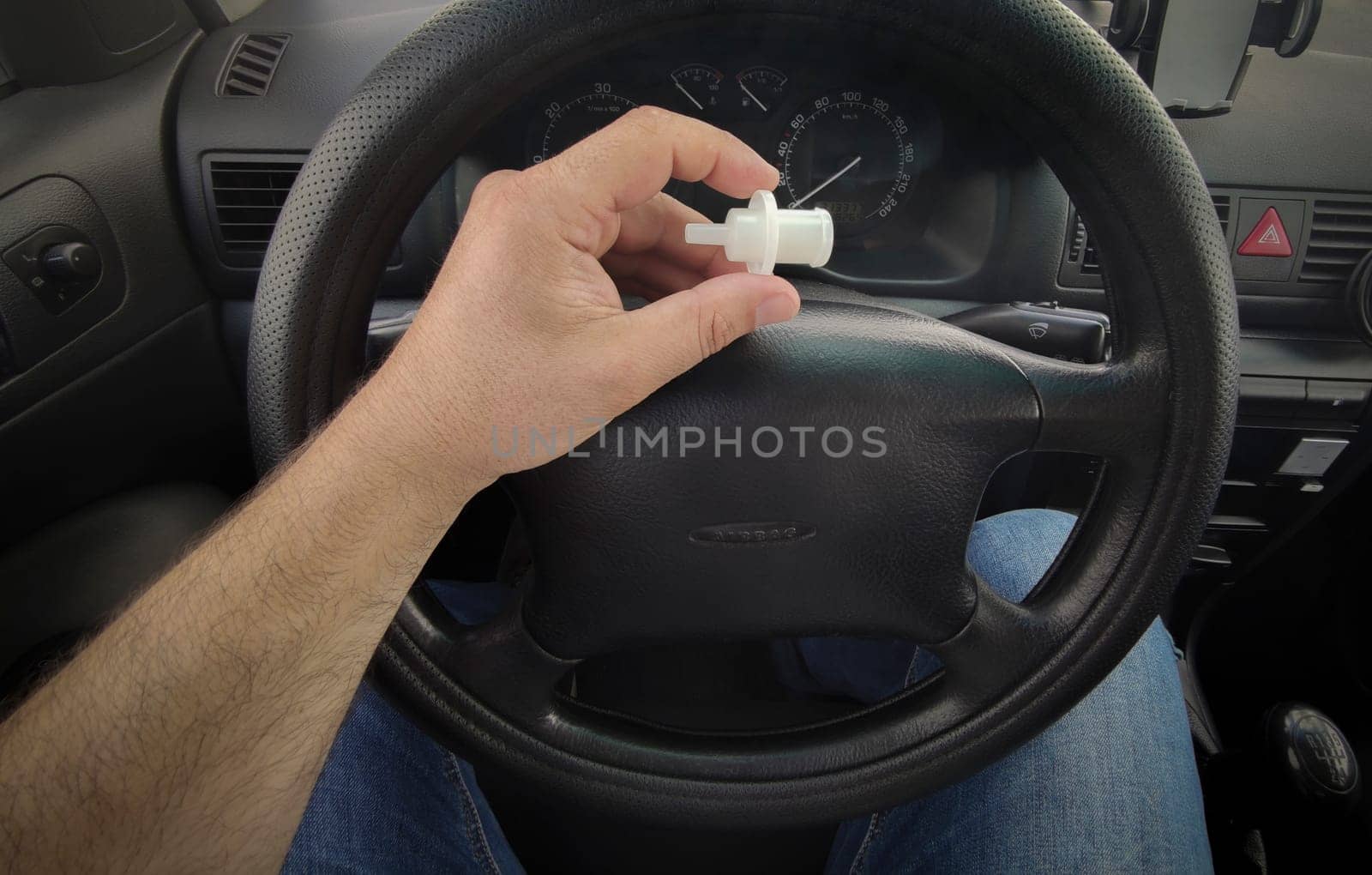 Driver holds breathalyzer mouthpiece sitting in the car. Point of view shot