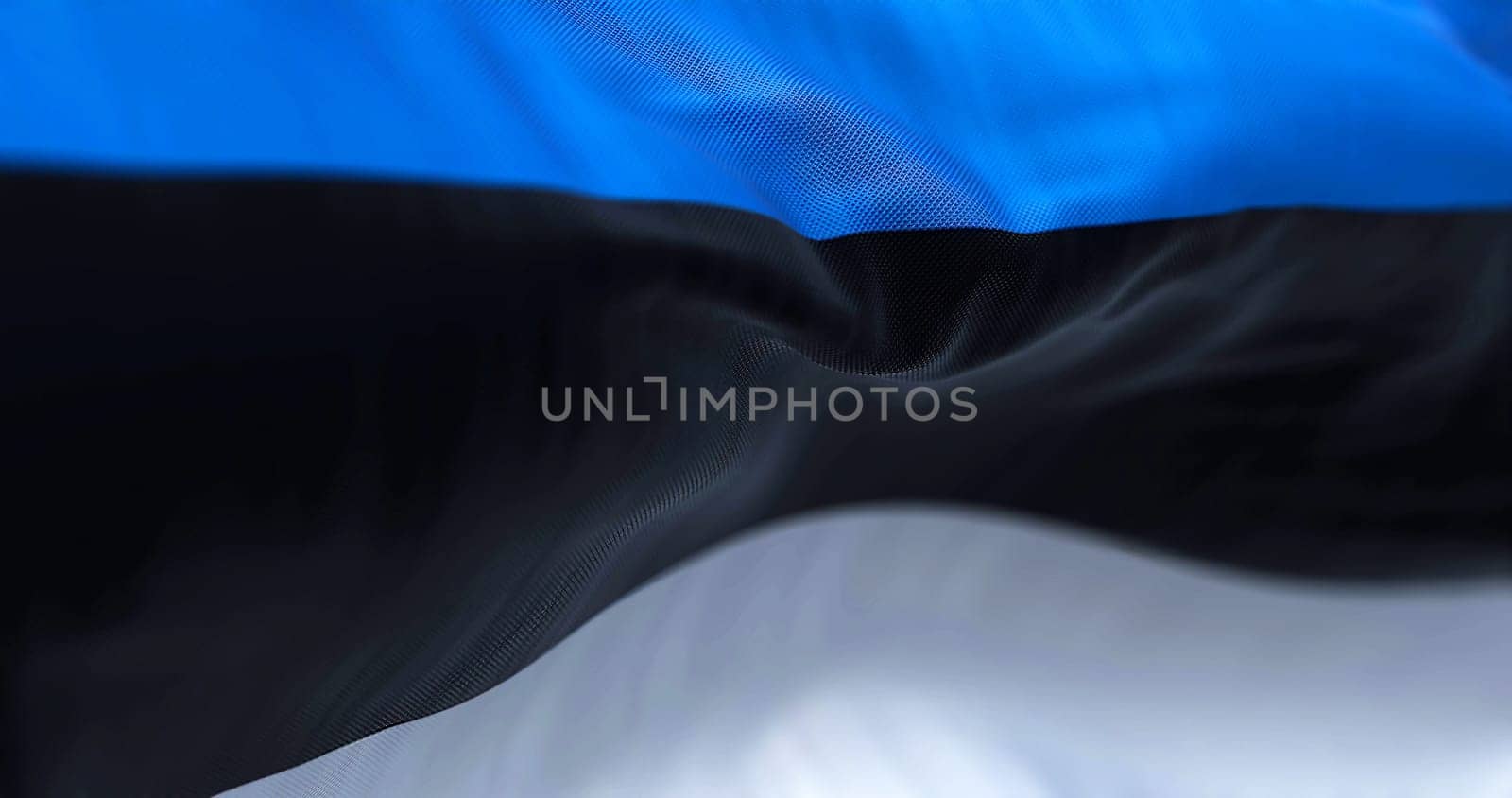 Close-up view of the estonian national flag waving in the wind. Estonia is a country in Northern Europe. Fabric textured background. Selective focus