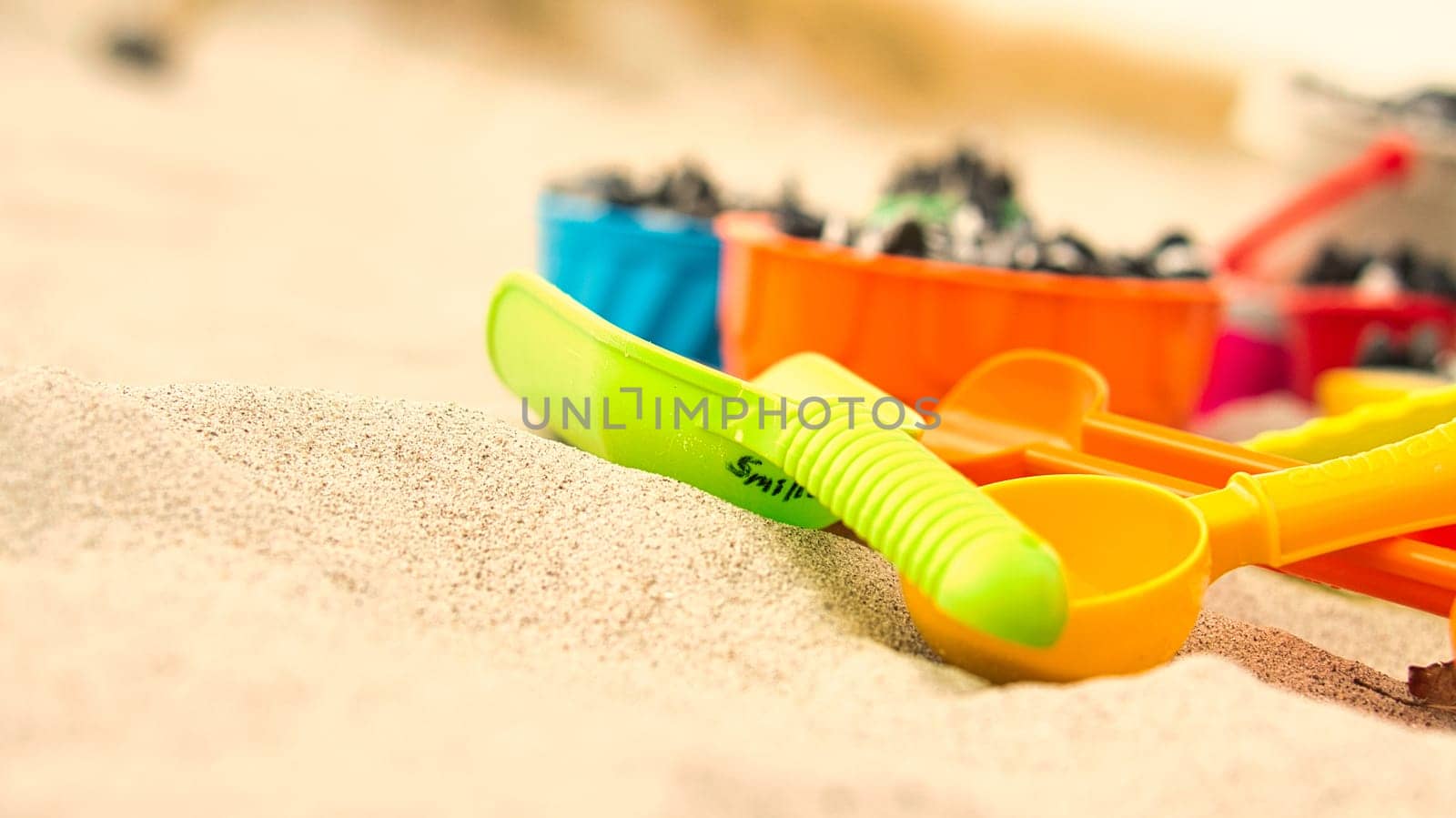 colorful toys on the beach for children to dig. Sand is used to build castles and shapes. Beach vacation with the family and fun for the little kids.