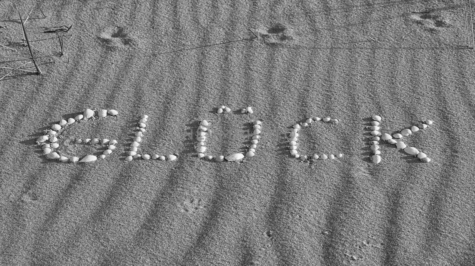 with shells laid symbol happiness on the beach of the Baltic Sea in the sand. In black and white. Wishes for the vacation and life.