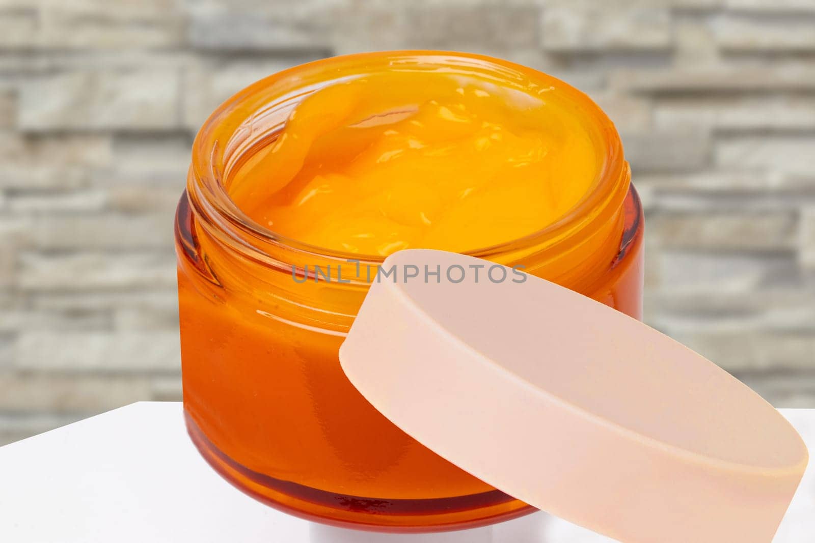 Closeup of an cosmetic jar of concealer cream, makeup foundation, moisturising cream for the face on table or other beauty make-up product over stone wall. Cosmetic label.