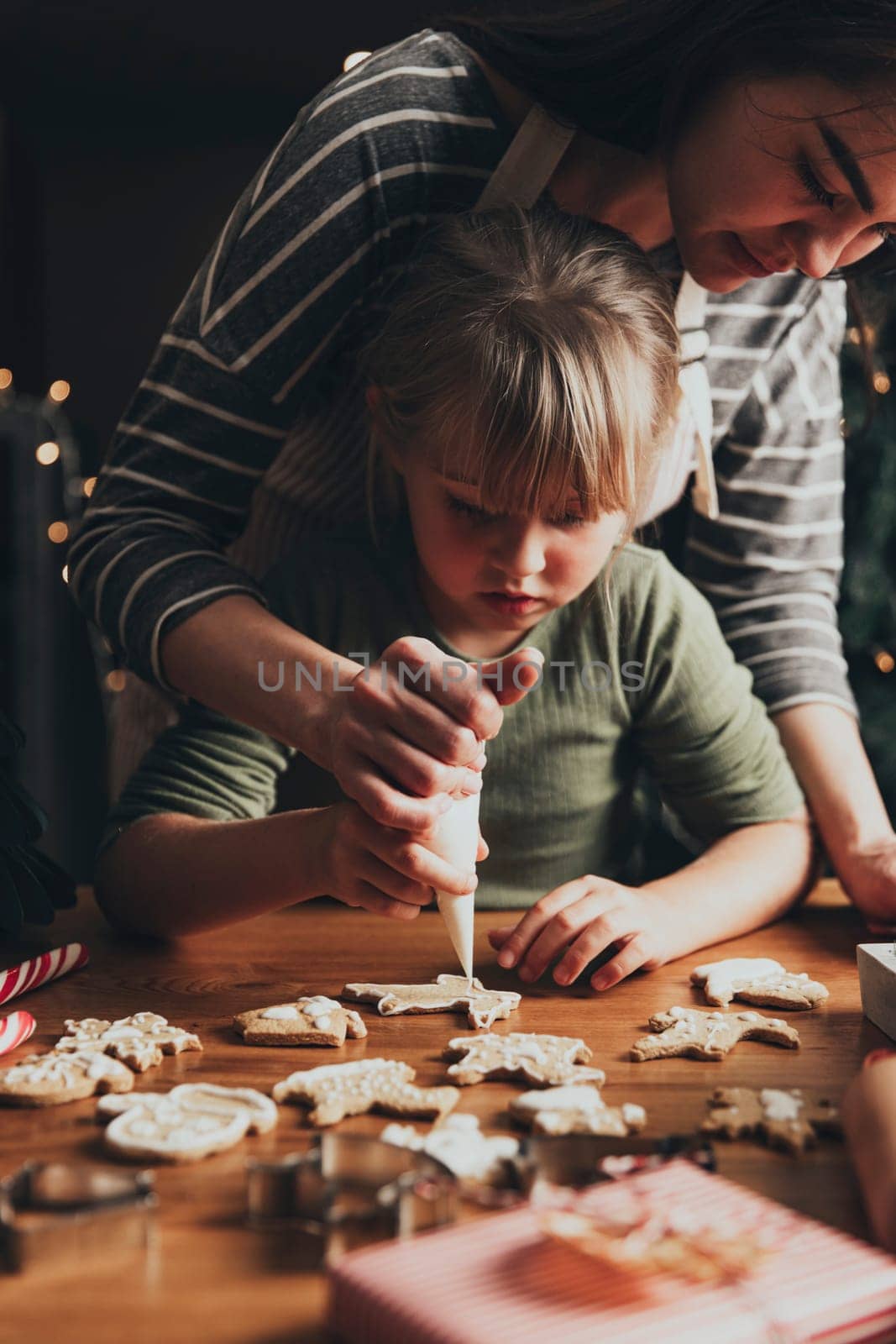 Christmas and New Year food preparation. Xmas gingerbread cooking, making and decorating freshly baked cookies with icing and mastic. Mommy and child, authentic lovely moments. DIY, creativity concept