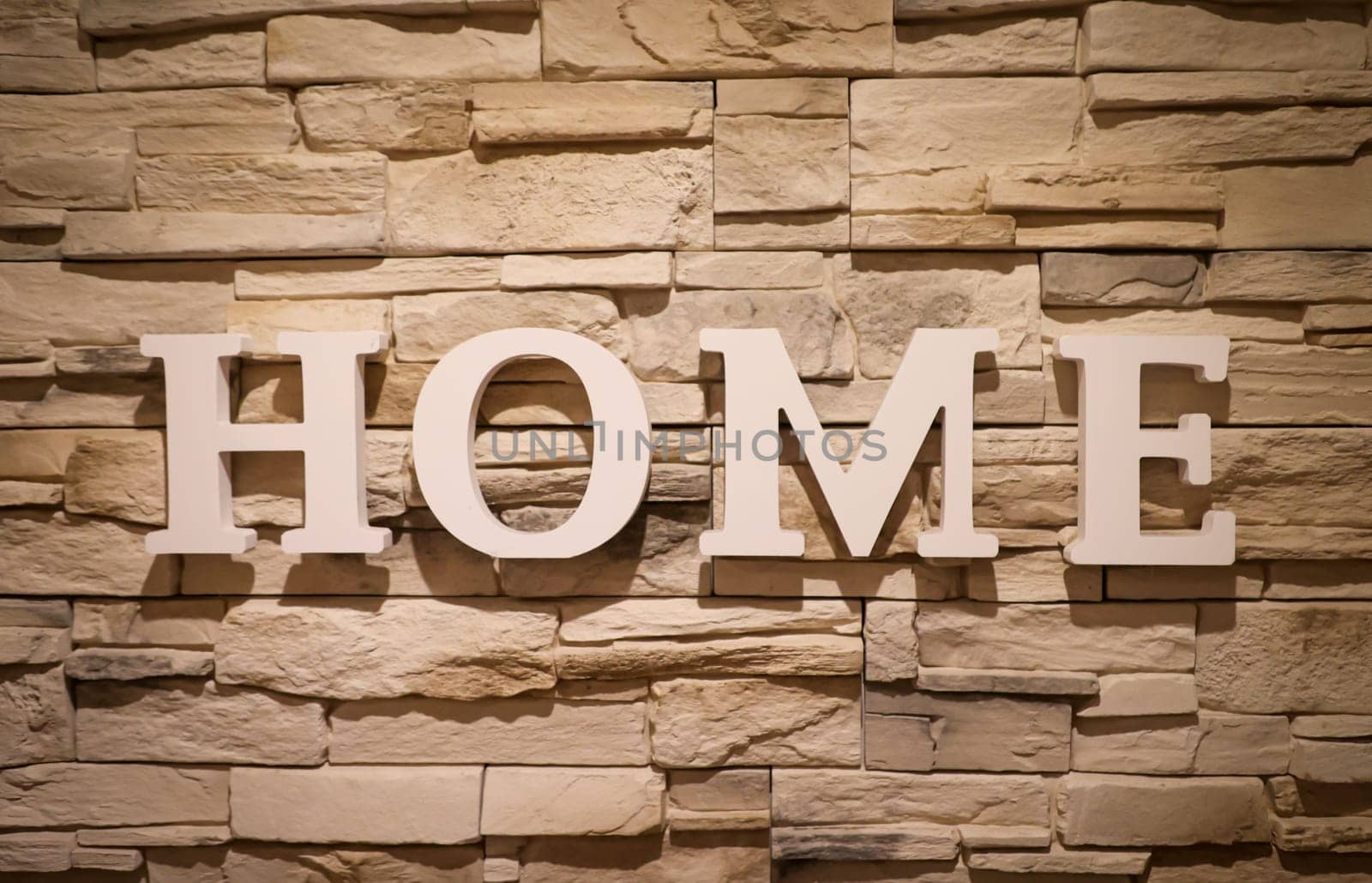 On a stone wall is attached lettering "HOME"". Stone texture."