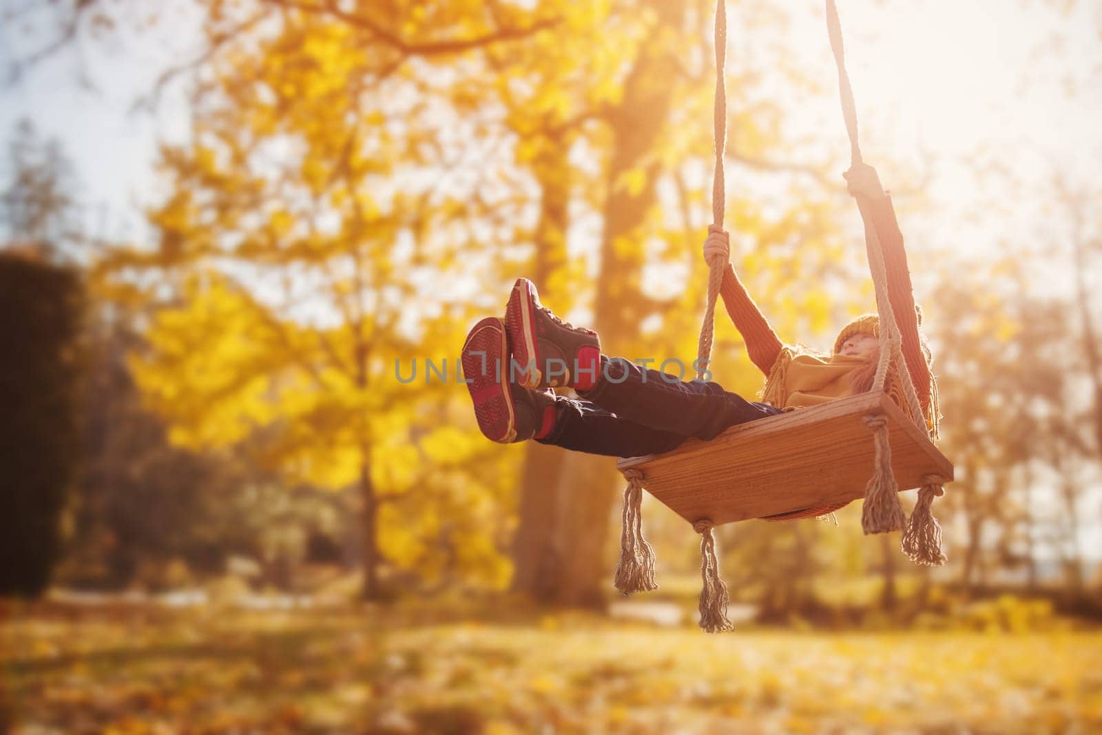 Cute girl swinging on the swing n the sunny park. Concept of the healthy lifestyle.