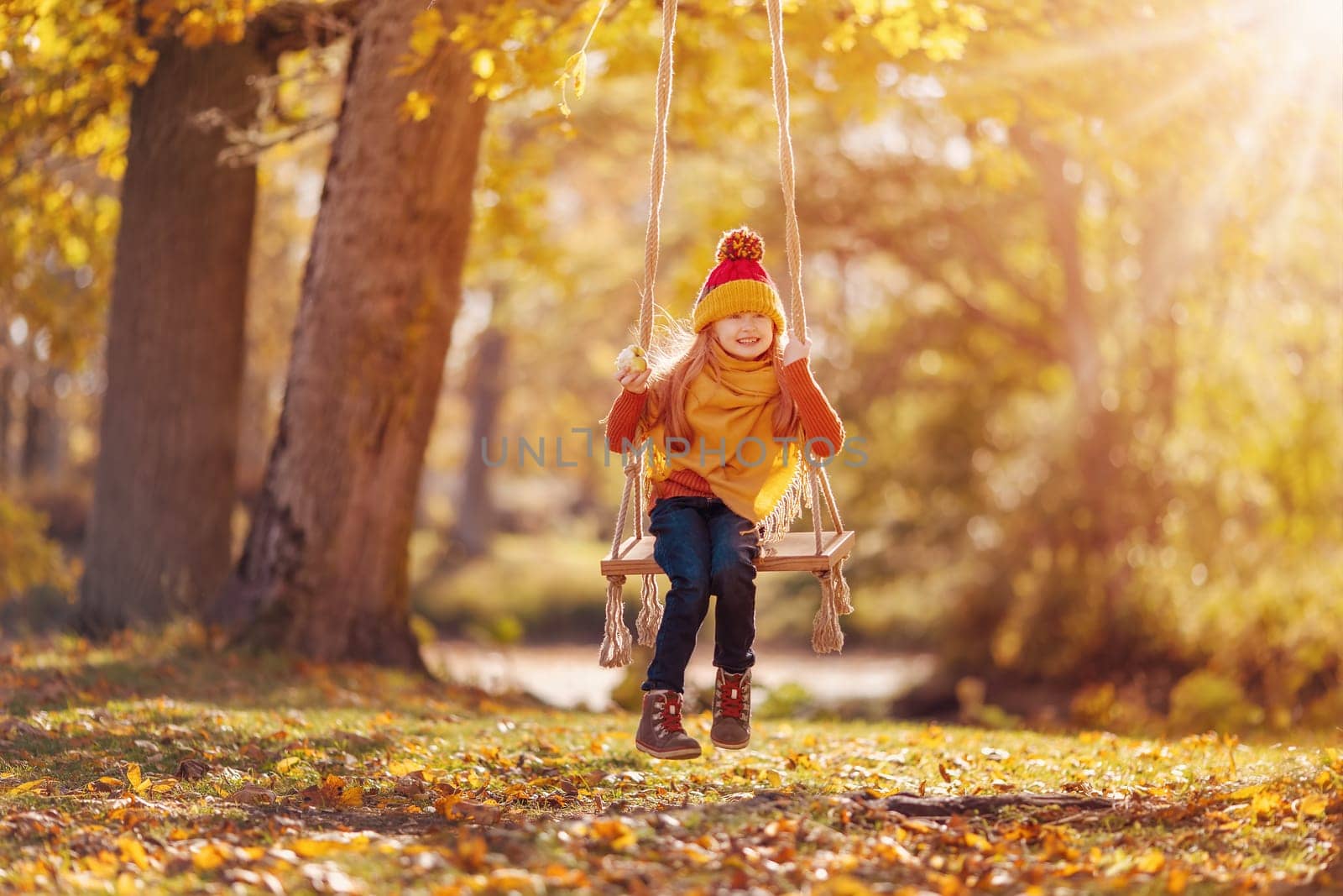 Cute girl swinging on the swing n the sunny park. Concept of the healthy lifestyle.