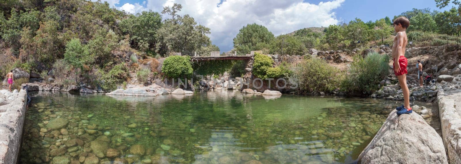 Child boy at La Maquina Natural swimming pool. Crystal-clear waters spot in the heart of La Vera County, Caceres, Extremadura, Spain