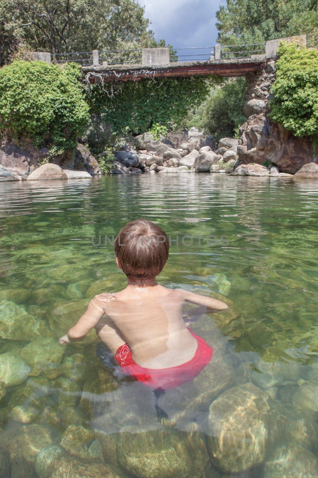 Child boy at La Maquina Natural swimming pool. Crystal-clear waters spot in the heart of La Vera County, Caceres, Extremadura, Spain