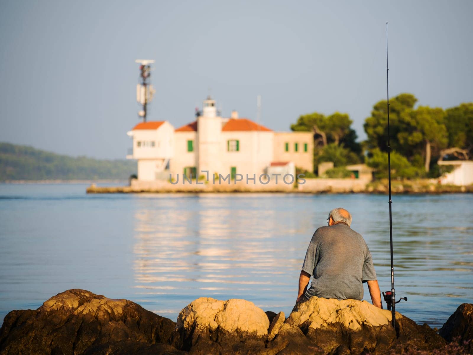 pensioner is sitting and fishing on canal of sveti ante in sibenik croatia