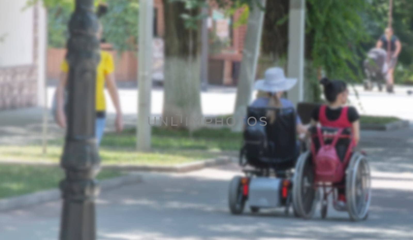 The blurred view of two disabled person on an electric wheelchair on a city street .