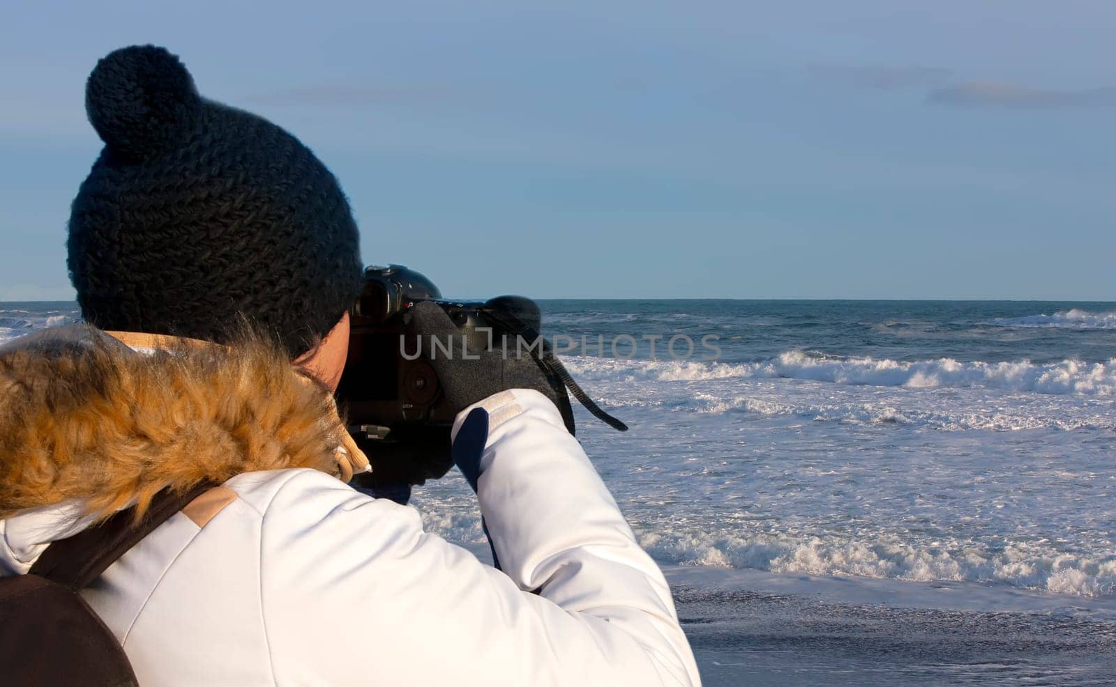 The young woman photographing waves on Pacific ocean on Kamchatka Peninsula