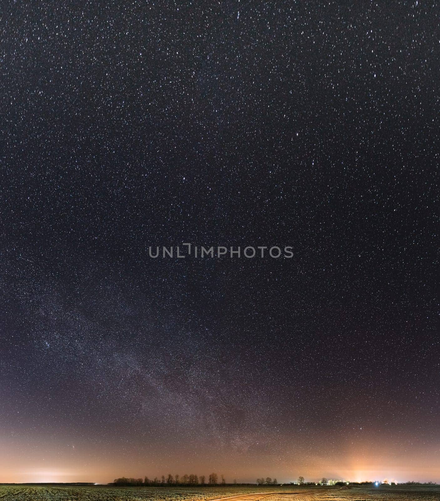 Night Starry Sky With Glowing Stars Above Countryside Landscape. Milky Way Galaxy And Rural Field Meadow In Early Spring.