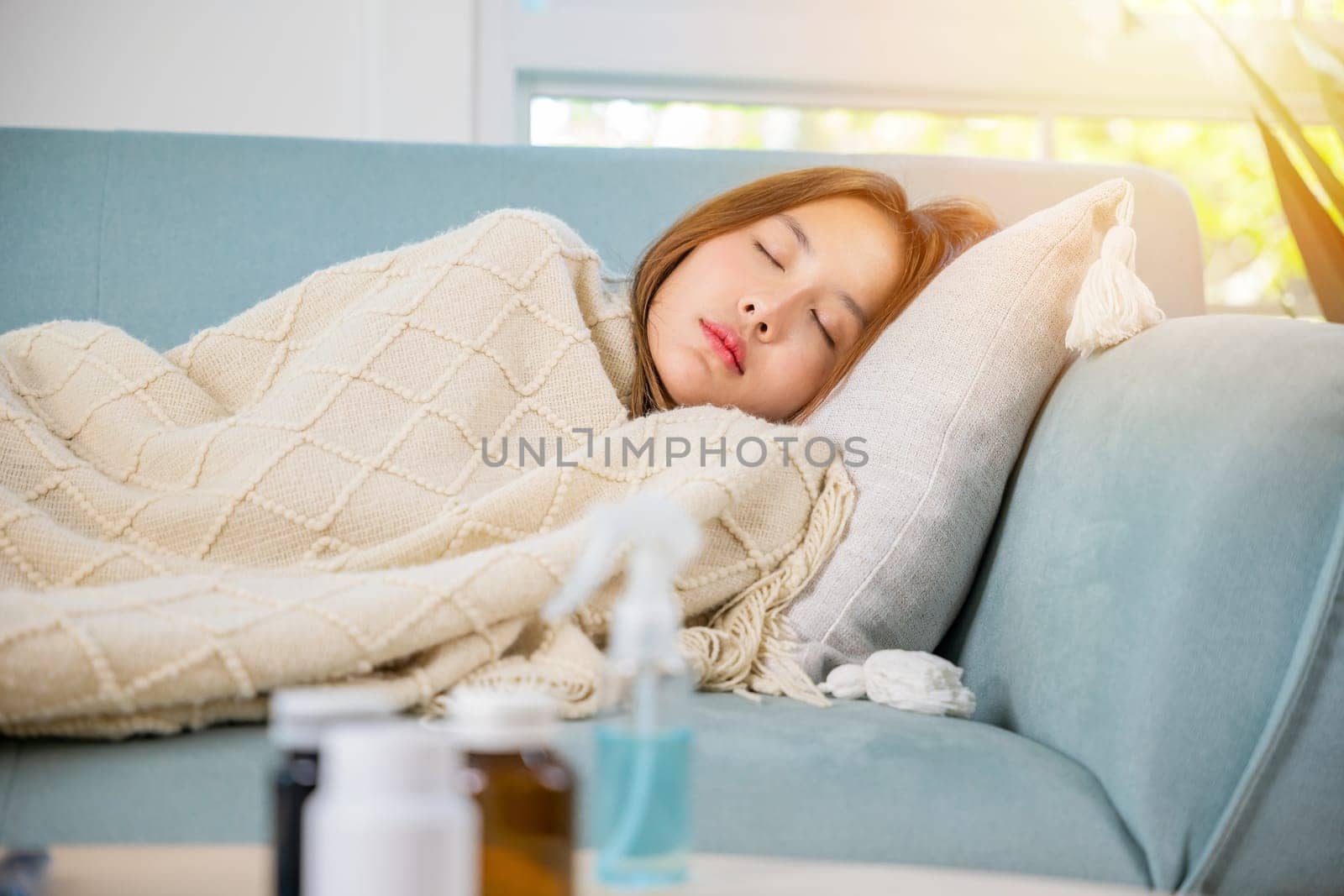Asian young woman tired sick she sleep and resting on sofa after take medicines pills in living room at home, beautiful female use pharmacy first aid kit box delivery service from hospital, healthcare