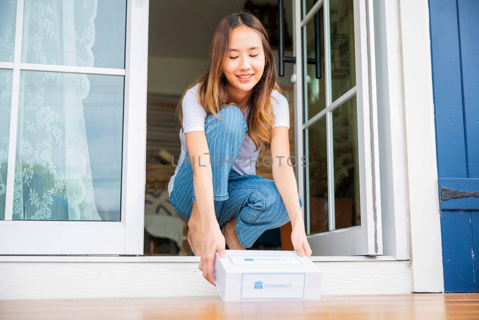 Close up hands of sick Asian woman sitting at door to receive medication first aid pharmacy box package from hospital delivery service at floor home, drugstore internet online medical business