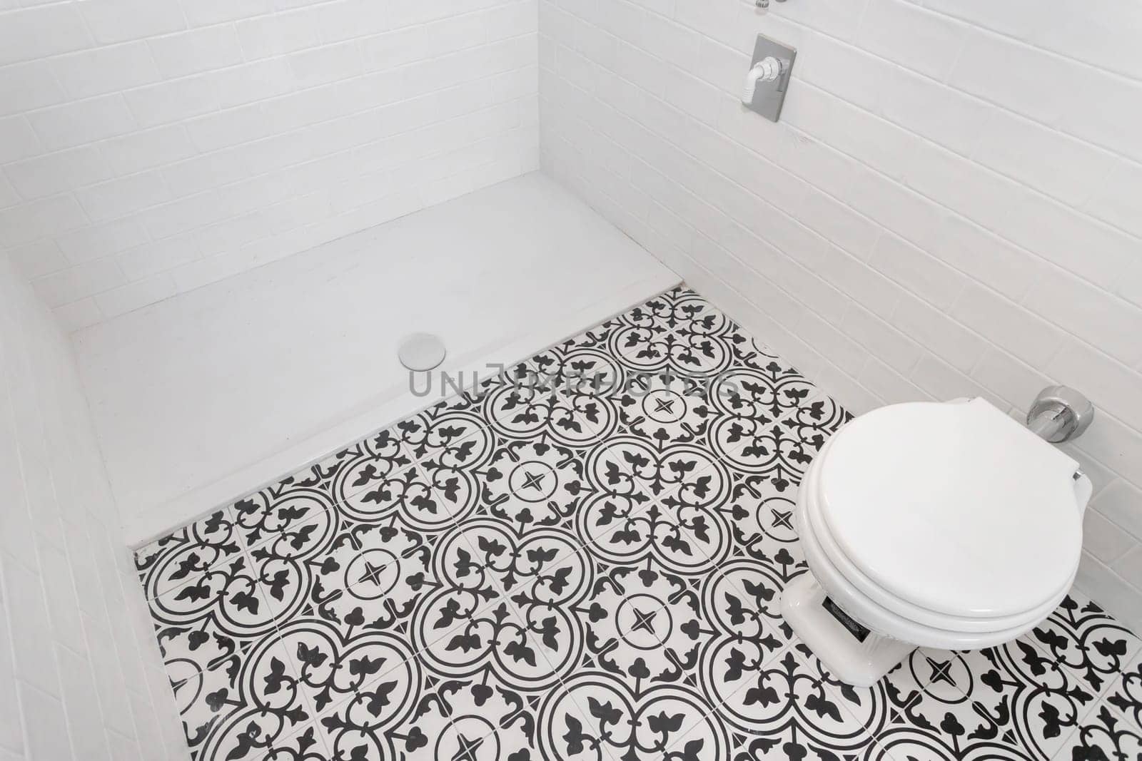 White ceramic toilet at luxury bathroom, with decored floor tiles. Italian style.