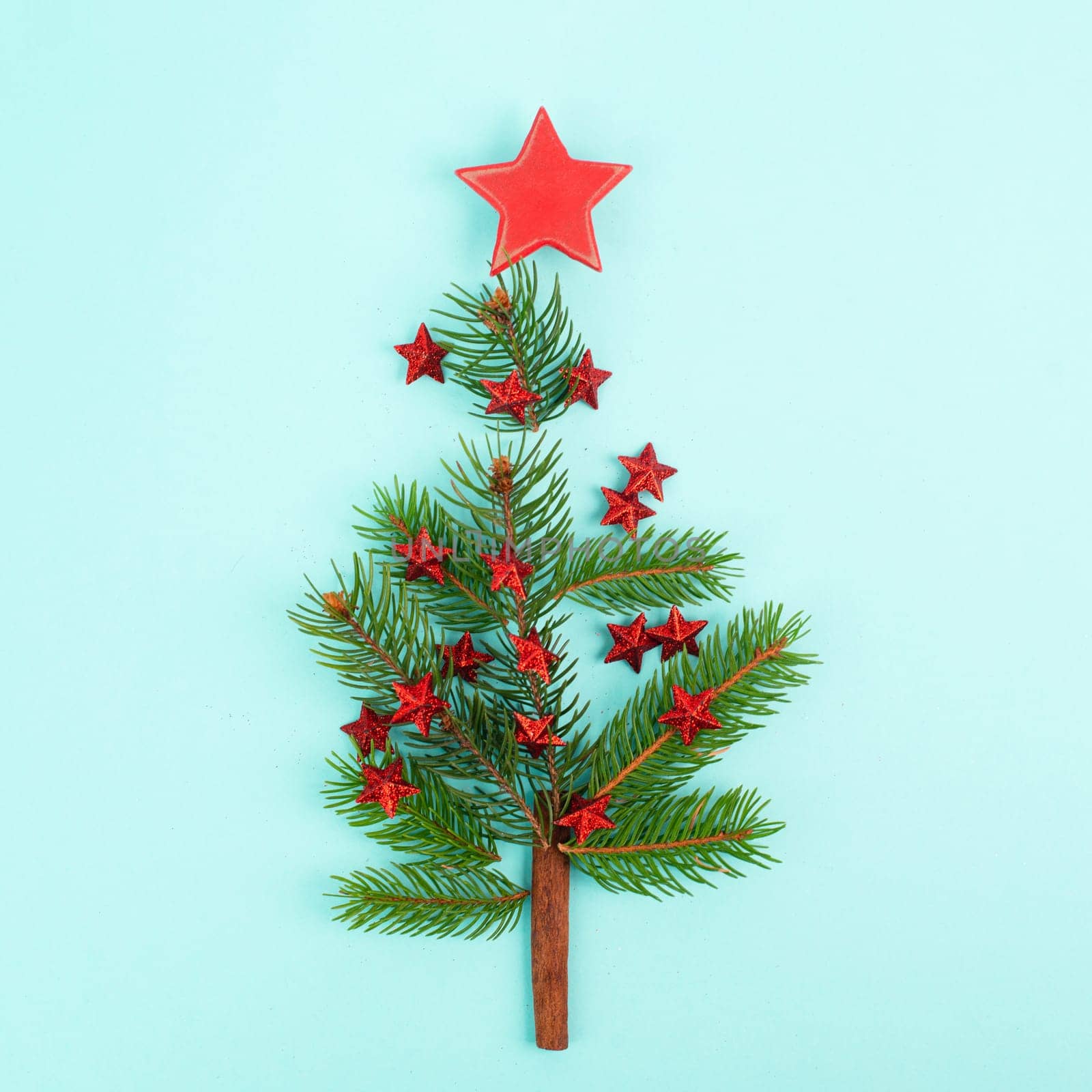 Christmas tree made from fir branches, red stars and a cinnamon stick as the trunk, greeting card with copy space