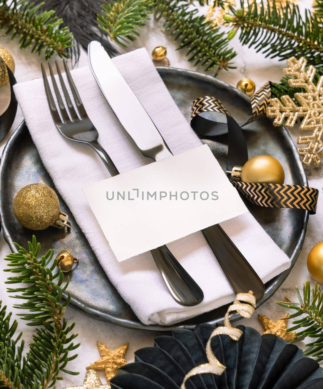 Black and golden Table setting with ornaments and fir tree branches close up, place card mockup. Christmas or New Year atmospheric composition flat lay, copy space.
