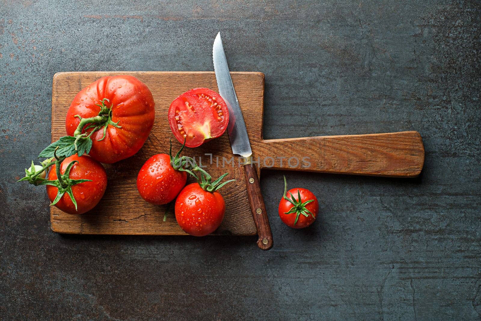Fresh tomatoes in cutting board on a dark background. Harvesting tomatoes. Cooking healthy meal.