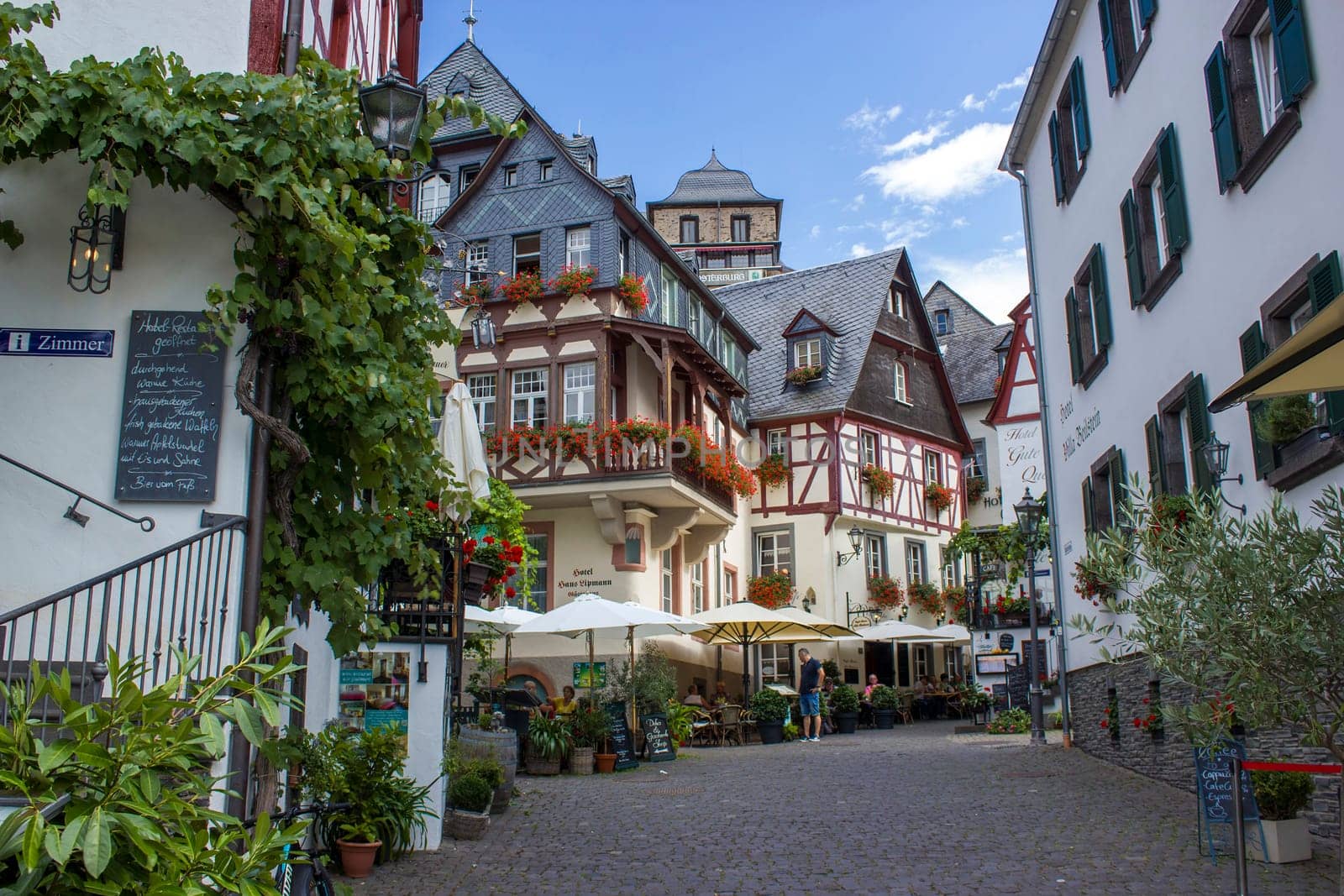 BEILSTEIN, GERMANY - SEPTEMBER 03 2022: historic village along the river Moselle with old half-timbered houses and the ruins of castle Metternich on top of the hills