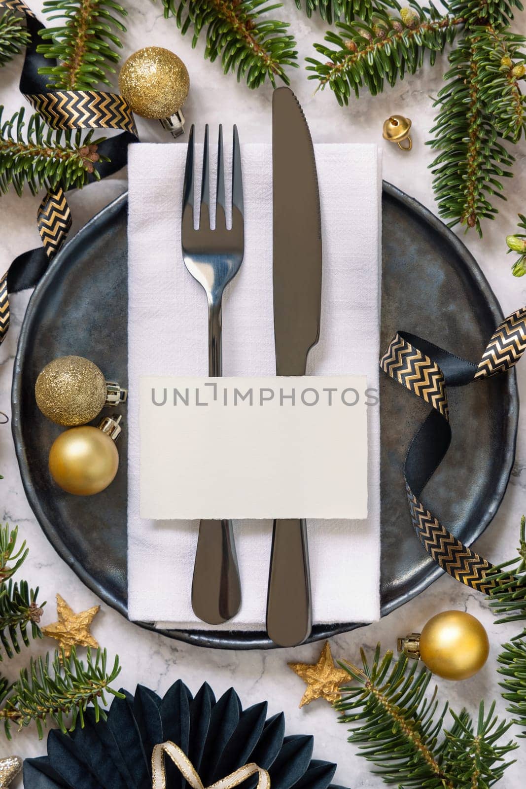 Black and golden Table setting with ornaments and fir tree branches top view, place card mockup. Christmas or New Year atmospheric composition flat lay, copy space.