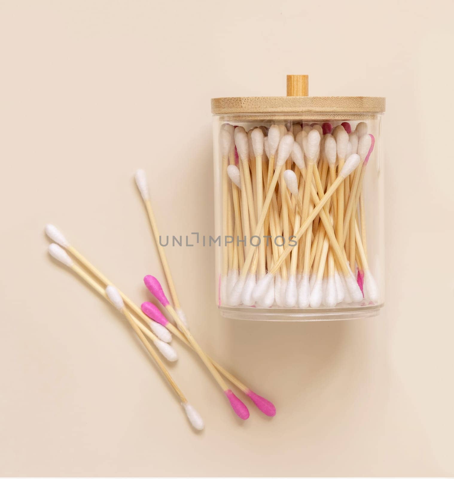 Bamboo cotton buds in a jar on light beige, top view. Organic skincare product for everyday beauty routine. Eco friendly Biodegradable cotton swabs..