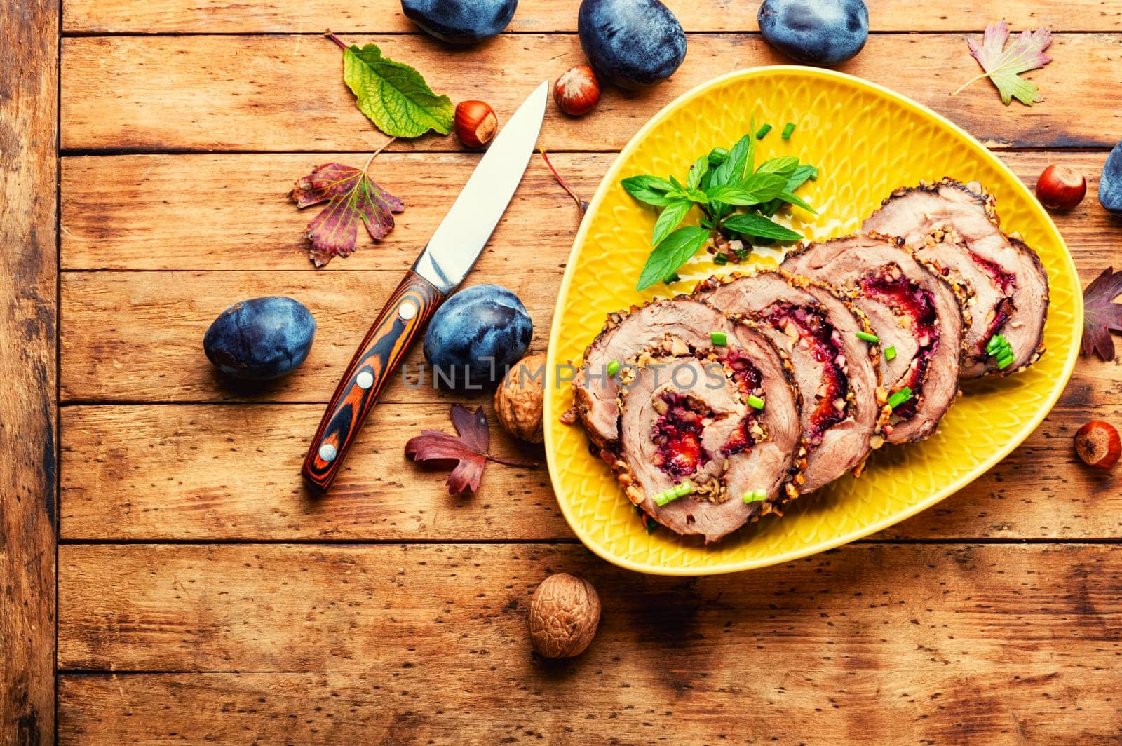 Appetizing roll roast with autumn plum and nuts.Pork porchetta.Copy space
