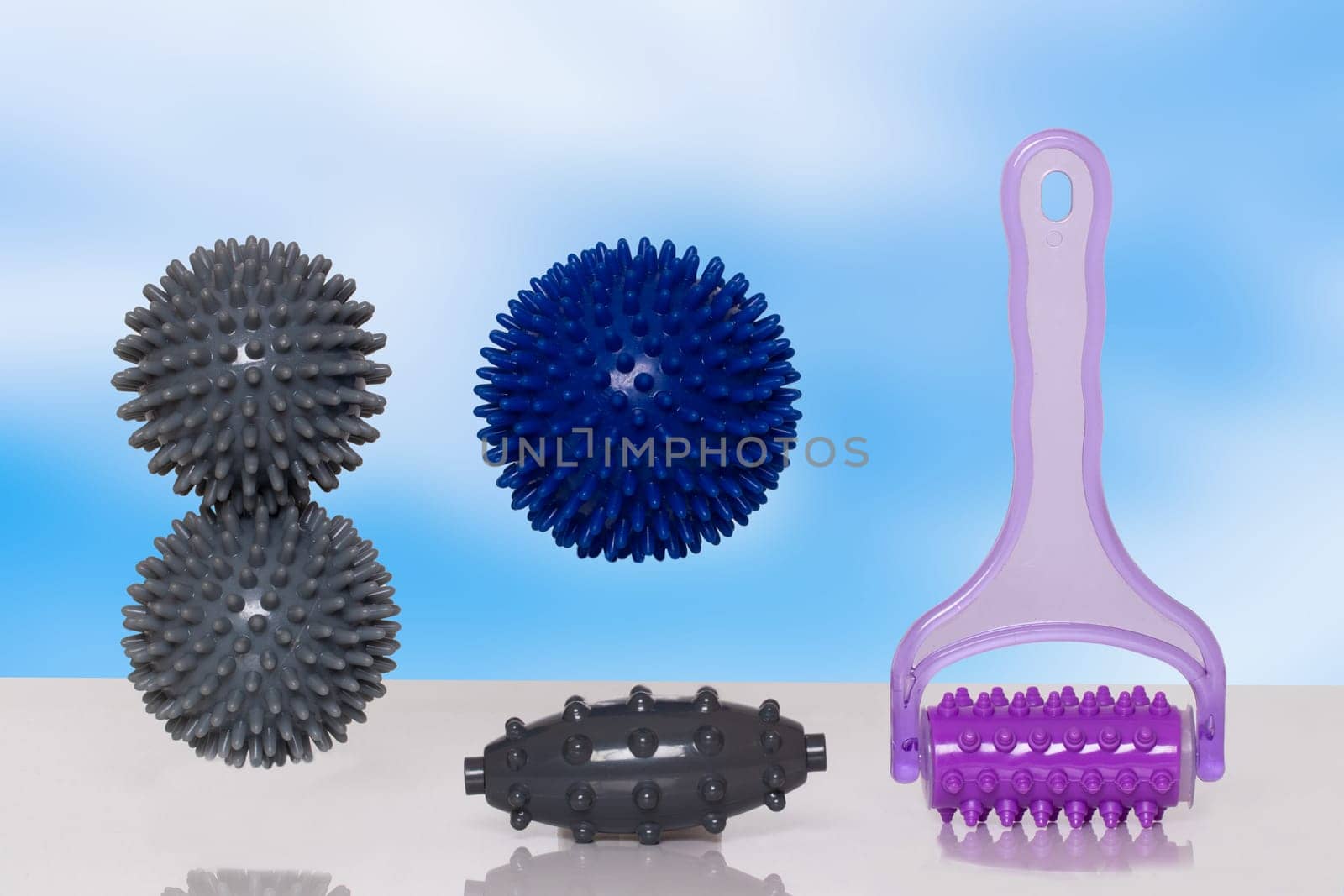 Closeup of various therapy and fitness equipment, such as massage balls or hedgehog balls and roller for health therapie on table over abstract background.