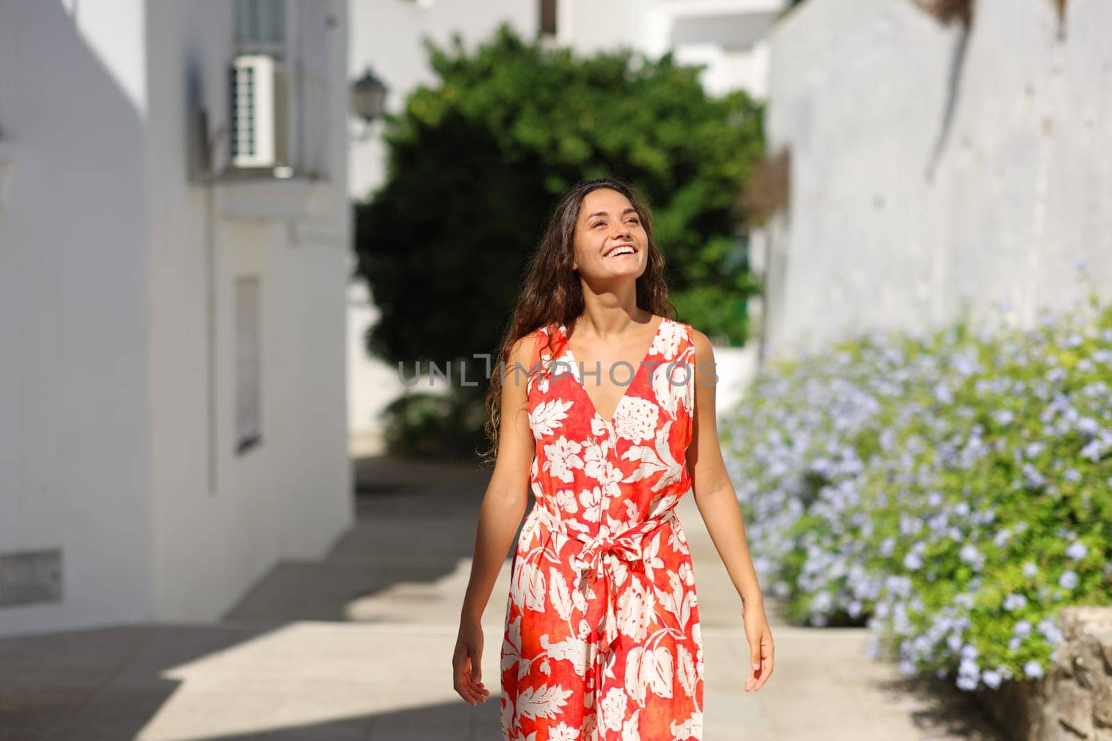 Front view portrait of a happy tourist walking sightseeing in a white town street on summer vacation