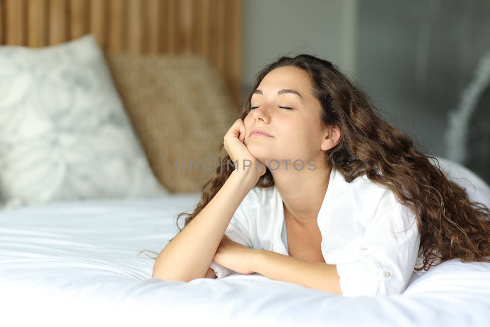 Woman with eyes closed relaxing lying on the bed