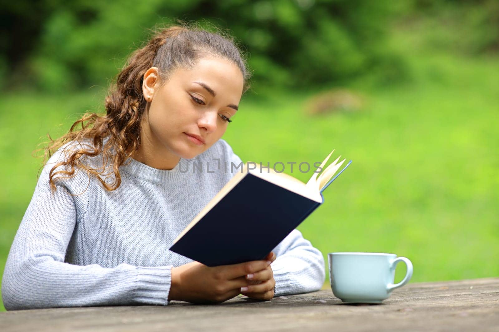 Relaxed woman in a park or camping reading a book