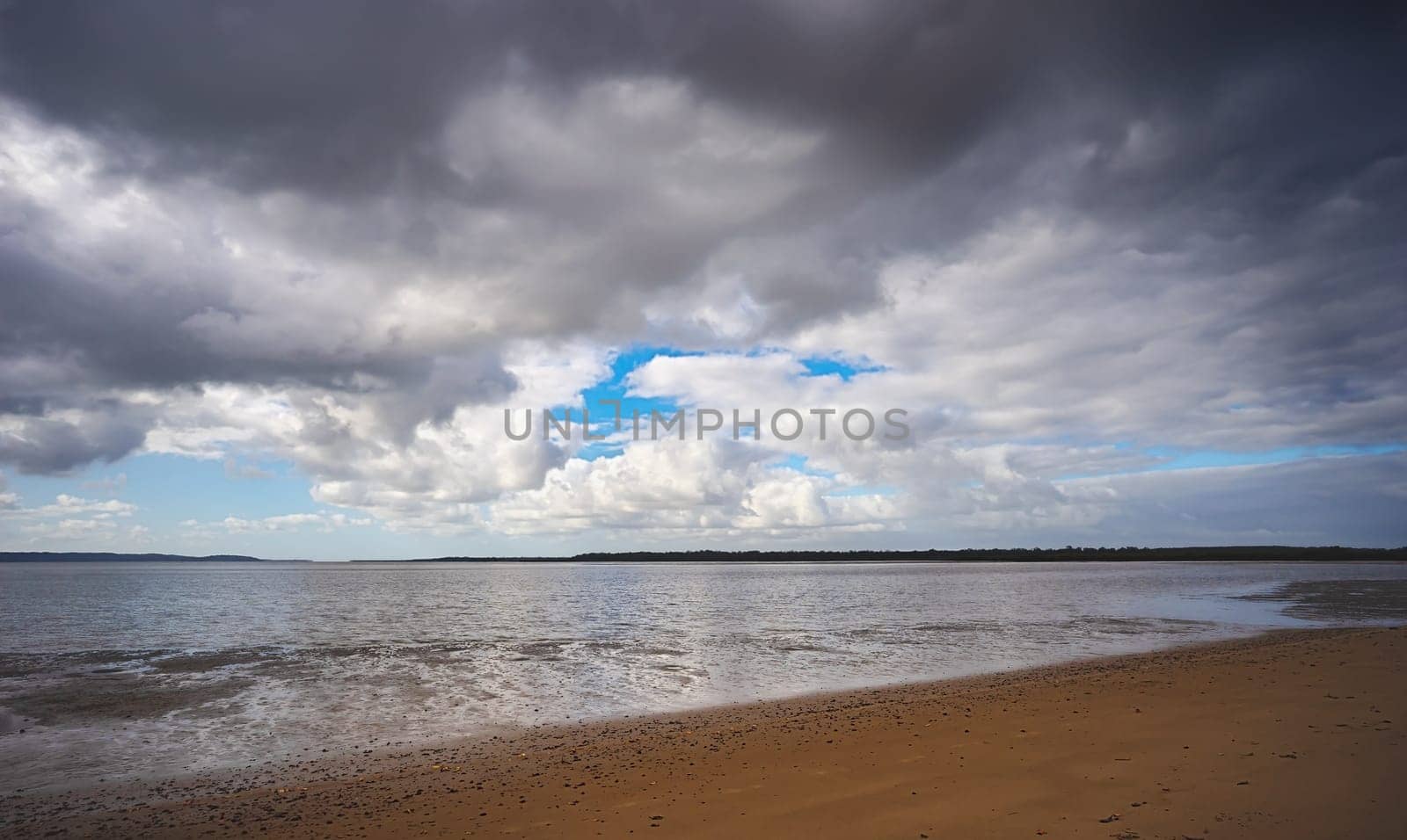 Threatening rain clouds forming over the Great Sandy Straits, Fraser Coast, Poona, Queensland. Mud flats are showing as the tide runs out.
