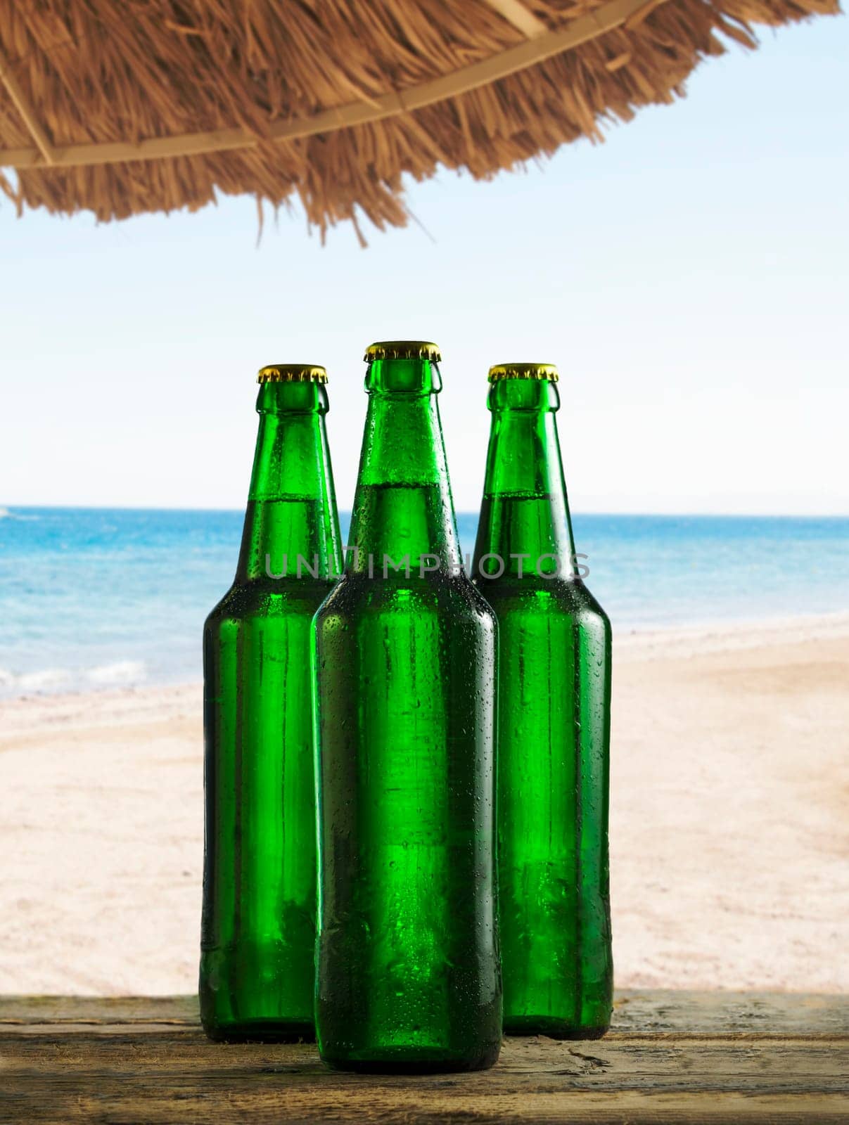 Refreshing cold beer bottles on beach bar table with water drops. Summer cocktail drink party on tropical island.