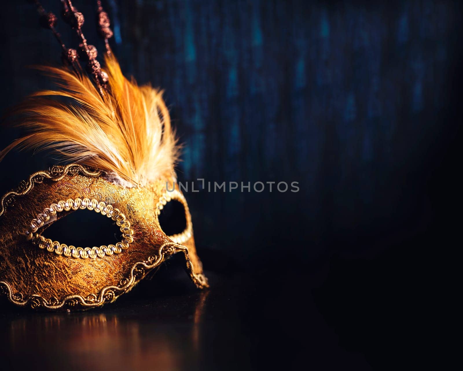 Golden venetian ball mask over dark background with copyspace. Masquerade party or holiday event celebration concept.