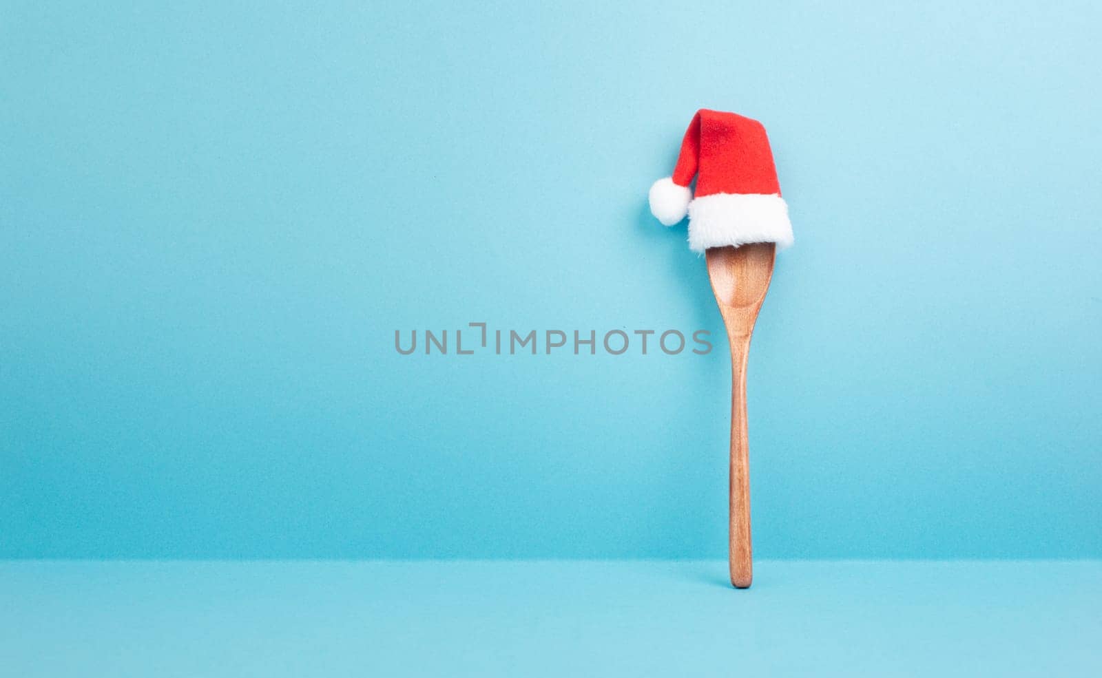 Blank paper with a wooden spoon and a red Santa Claus hat, christmas greeting card, copy space for a recipe for the holiday